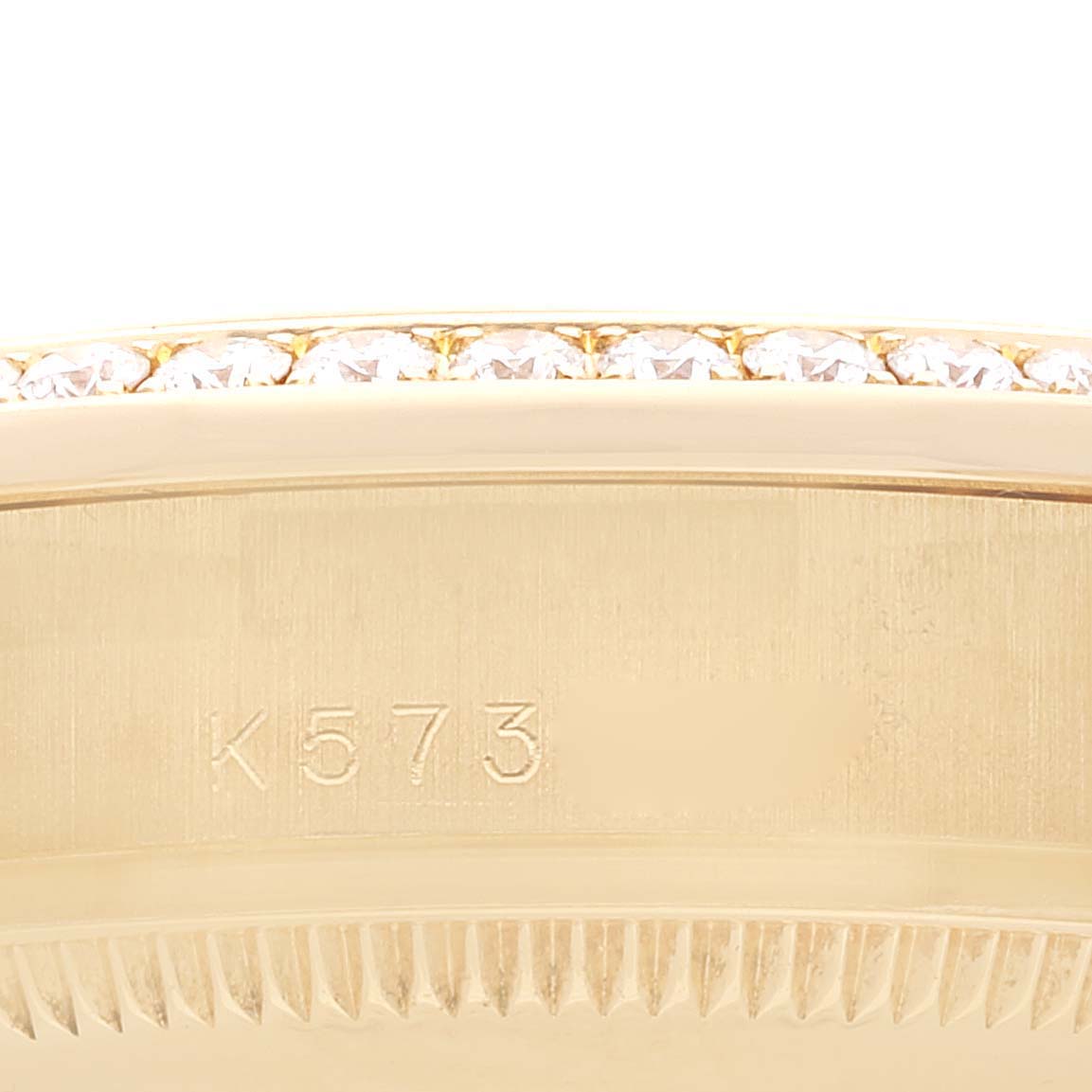 The image shows a close-up of the President model by Rolex, highlighting the bezel adorned with diamonds and part of the case with an engraving.