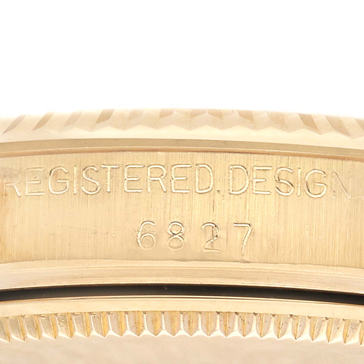 This close-up image shows the side of the caseback on a Rolex President M6827/8 Women's Yellow Gold Champagne Dial M6827/8 Women's Yellow Gold Champagne Dial watch, highlighting the "REGISTERED DESIGN" engraving and the serial number.