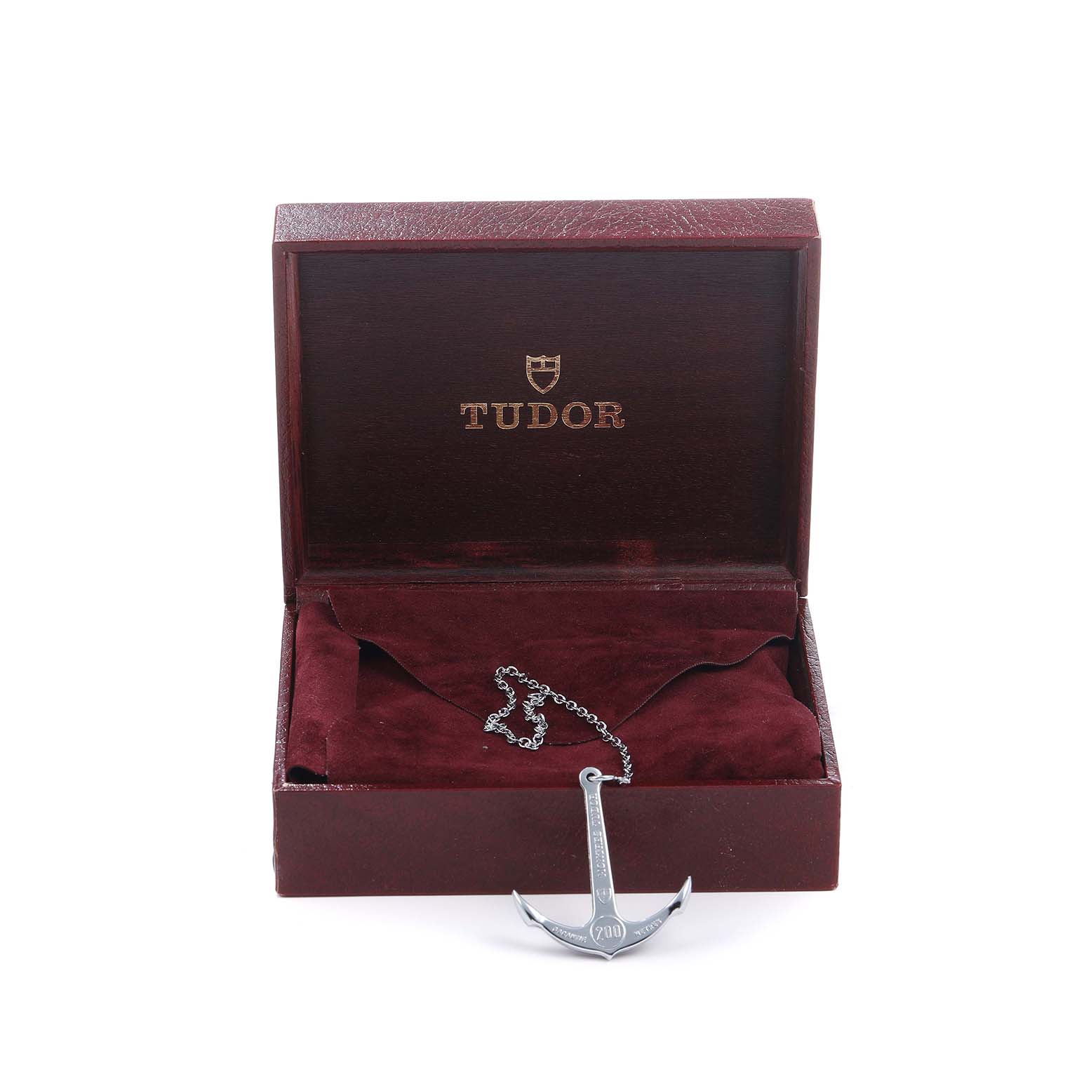 The image shows a Tudor Prince 73090 Men's Stainless Steel Black Dial model watch box, open with a metal anchor accessory on a chain inside.