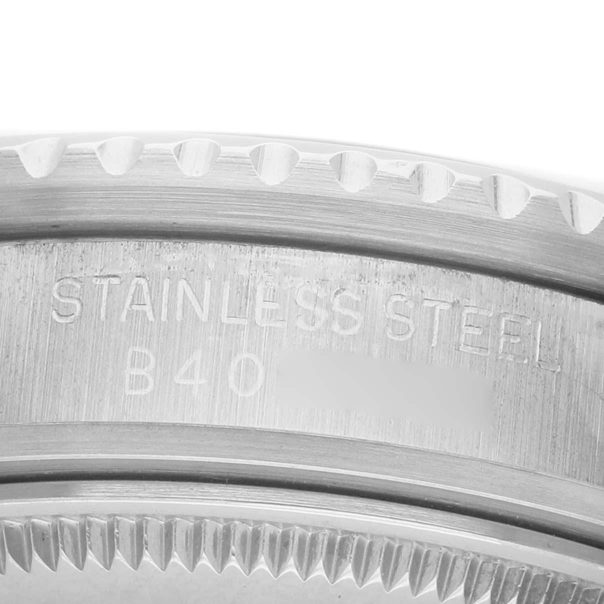 The image shows a close-up of the bezel's edge and the engraved text on the stainless steel back of the Tudor Prince 73090 Men's Stainless Steel Black Dial watch.