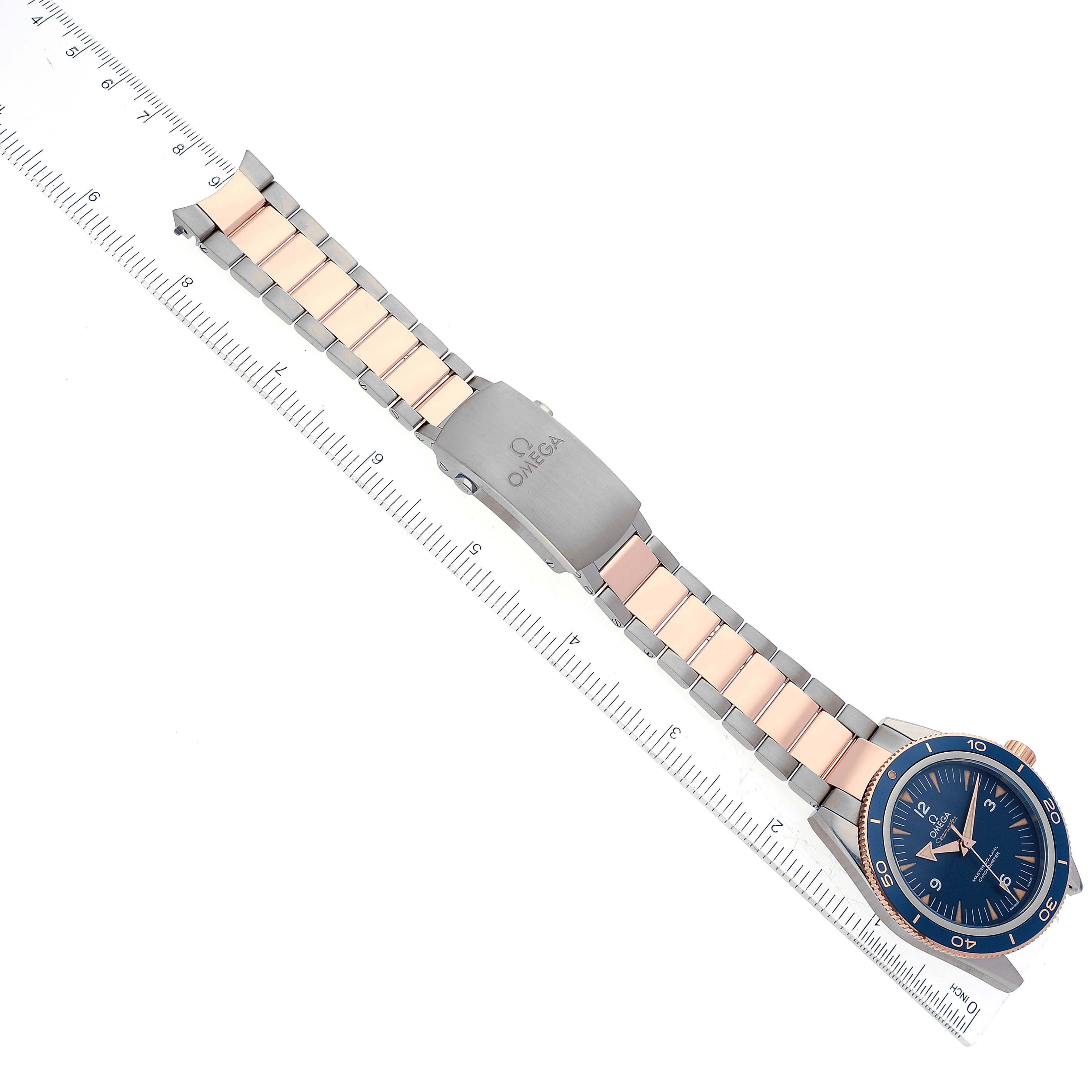 The Omega Seamaster 233.60.41.21.03.001 Men's Titanium Blue Dial 233.60.41.21.03.001 Men's Titanium Blue Dial watch is shown in a top-down view, featuring its face, bezel, bracelet, and clasp next to a ruler for scale.