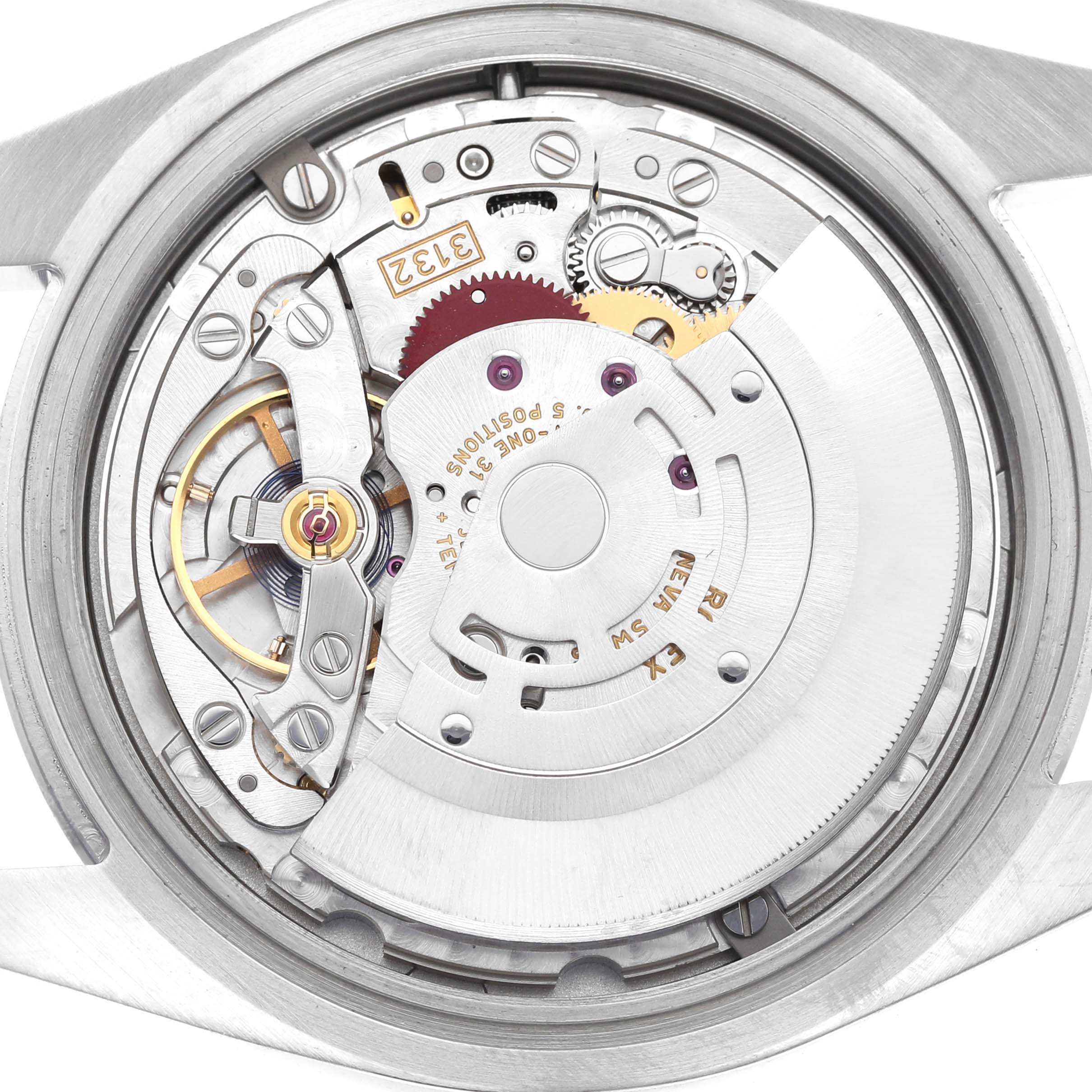 The image shows the movement of a Rolex Oyster Perpetual 114300 Men's Stainless Steel Blue Dial watch from the back, highlighting gears and mechanical components.