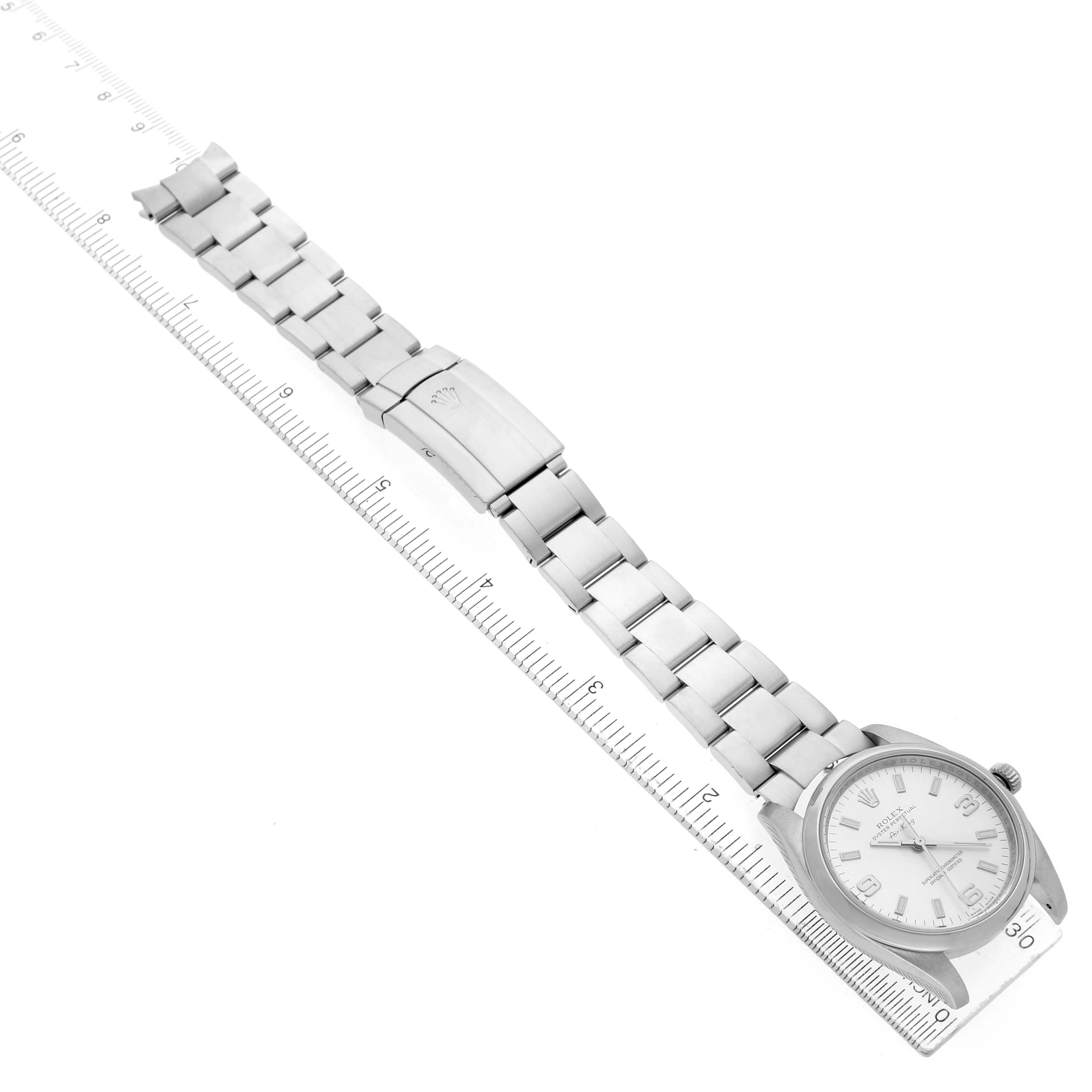 The Rolex Air-King 114200 Men's Stainless Steel Silver Dial watch is shown from the top, displaying the full bracelet, clasp, and face with a ruler for scale.