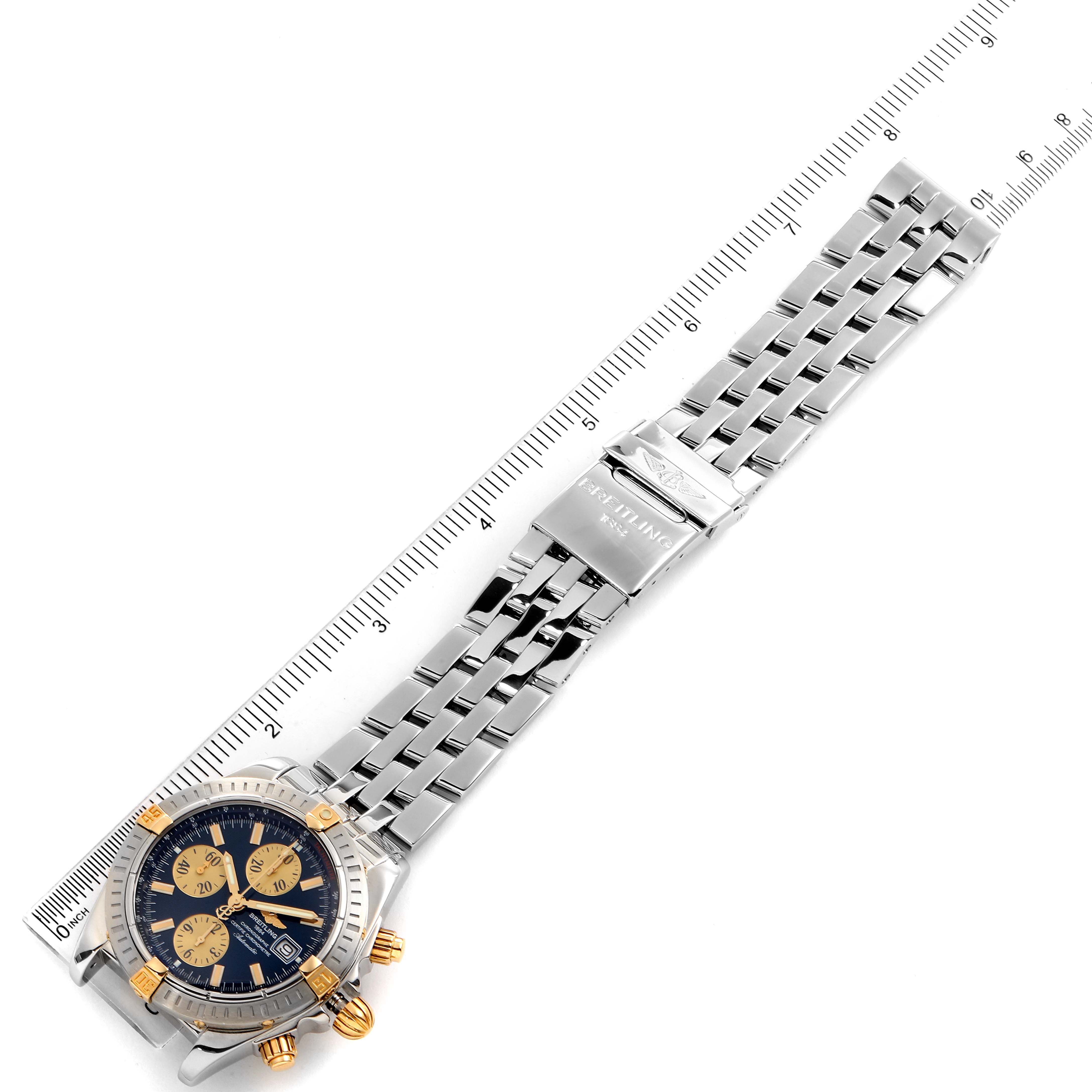 The image shows a top view of a Breitling Chronomat B13356 Men's Steel and Gold (two tone) Blue Dial B13356 Men's Steel and Gold (two tone) Blue Dial watch and its metal bracelet, laid alongside a measuring ruler.