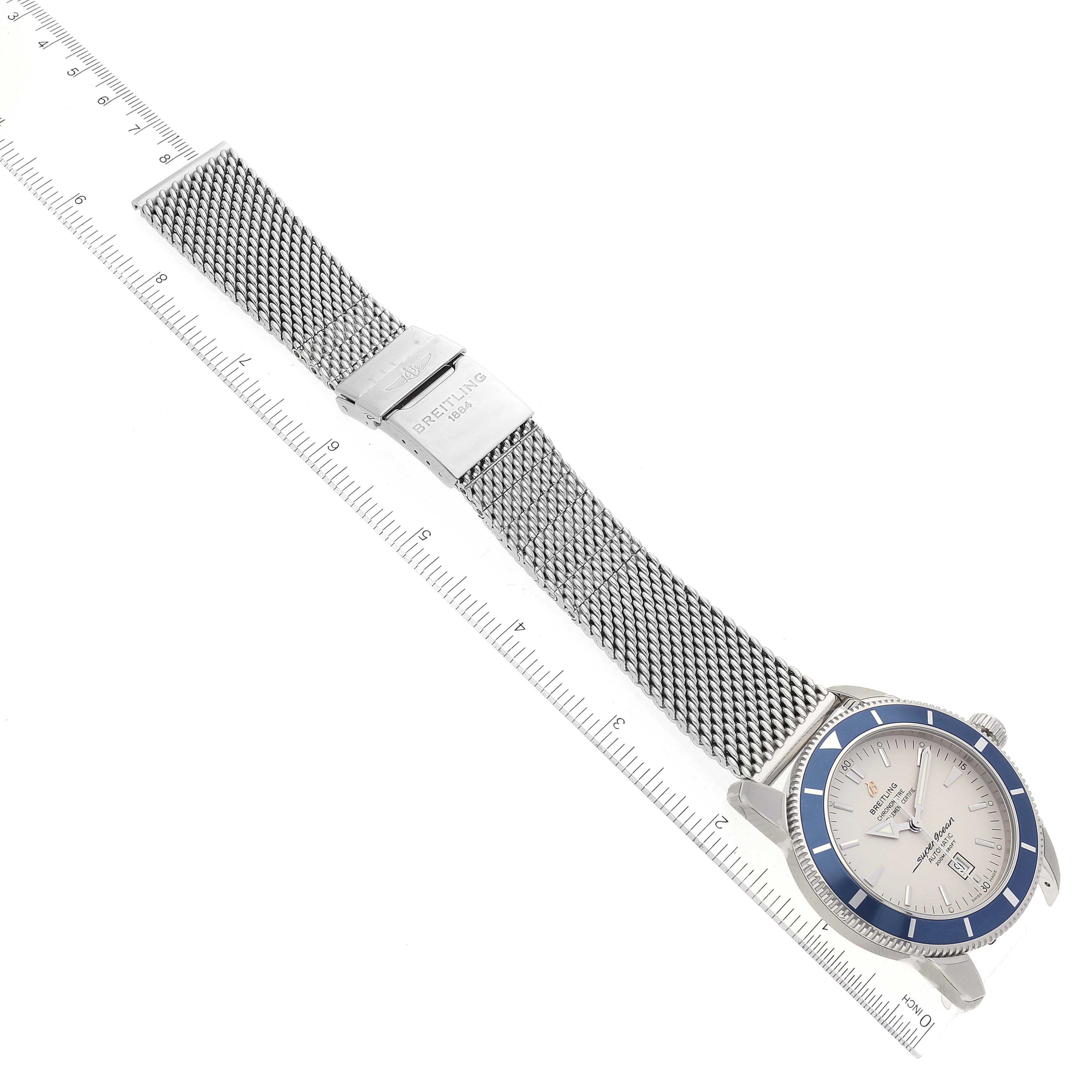 The image shows a Breitling Superocean A17320 Men's Stainless Steel Silver Dial A17320 Men's Stainless Steel Silver Dial watch laid flat, displaying its face, mesh bracelet, clasp, and a measurement ruler.
