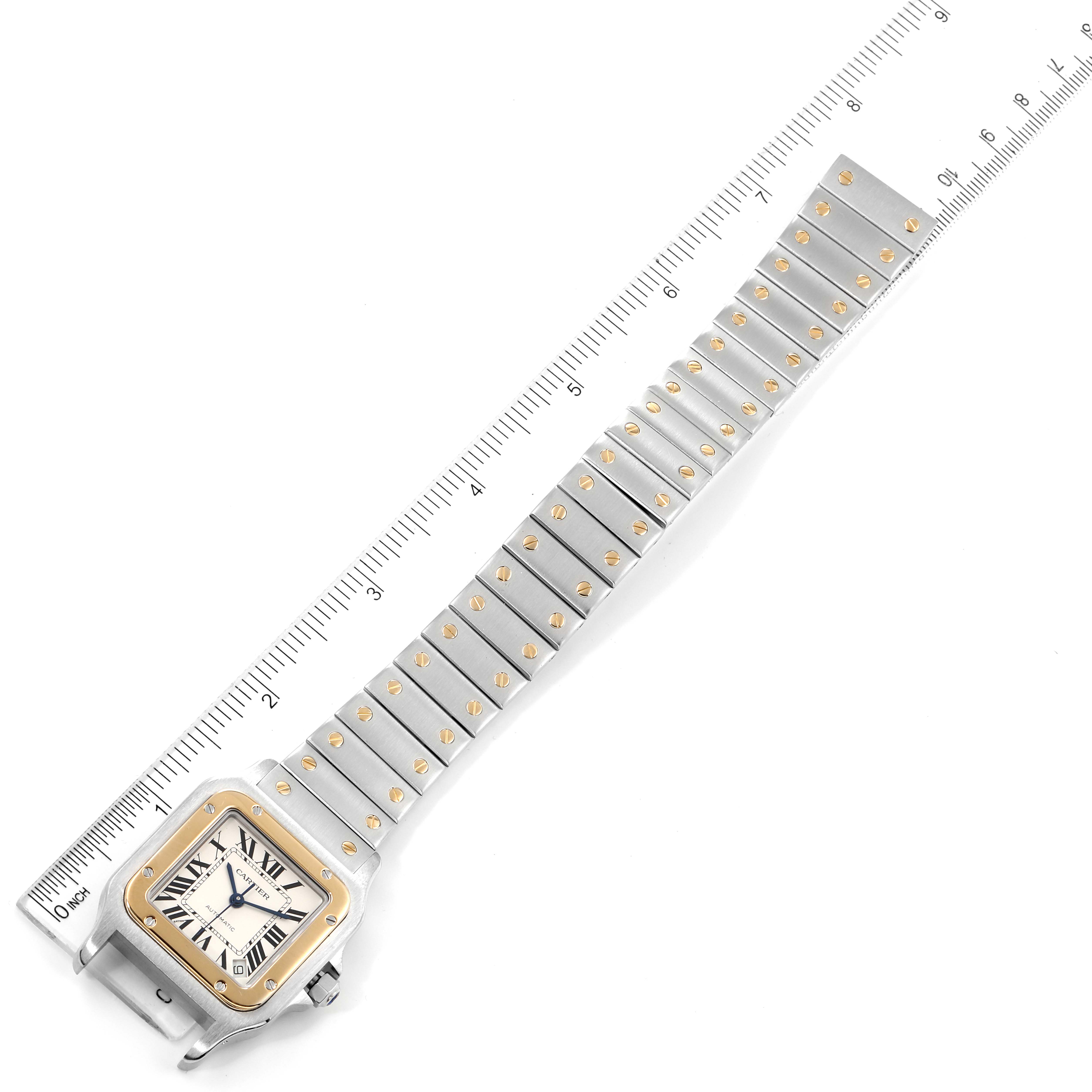 The image shows a top-down view of a Santos model by Cartier, highlighting the watch face and metal bracelet against a ruler.