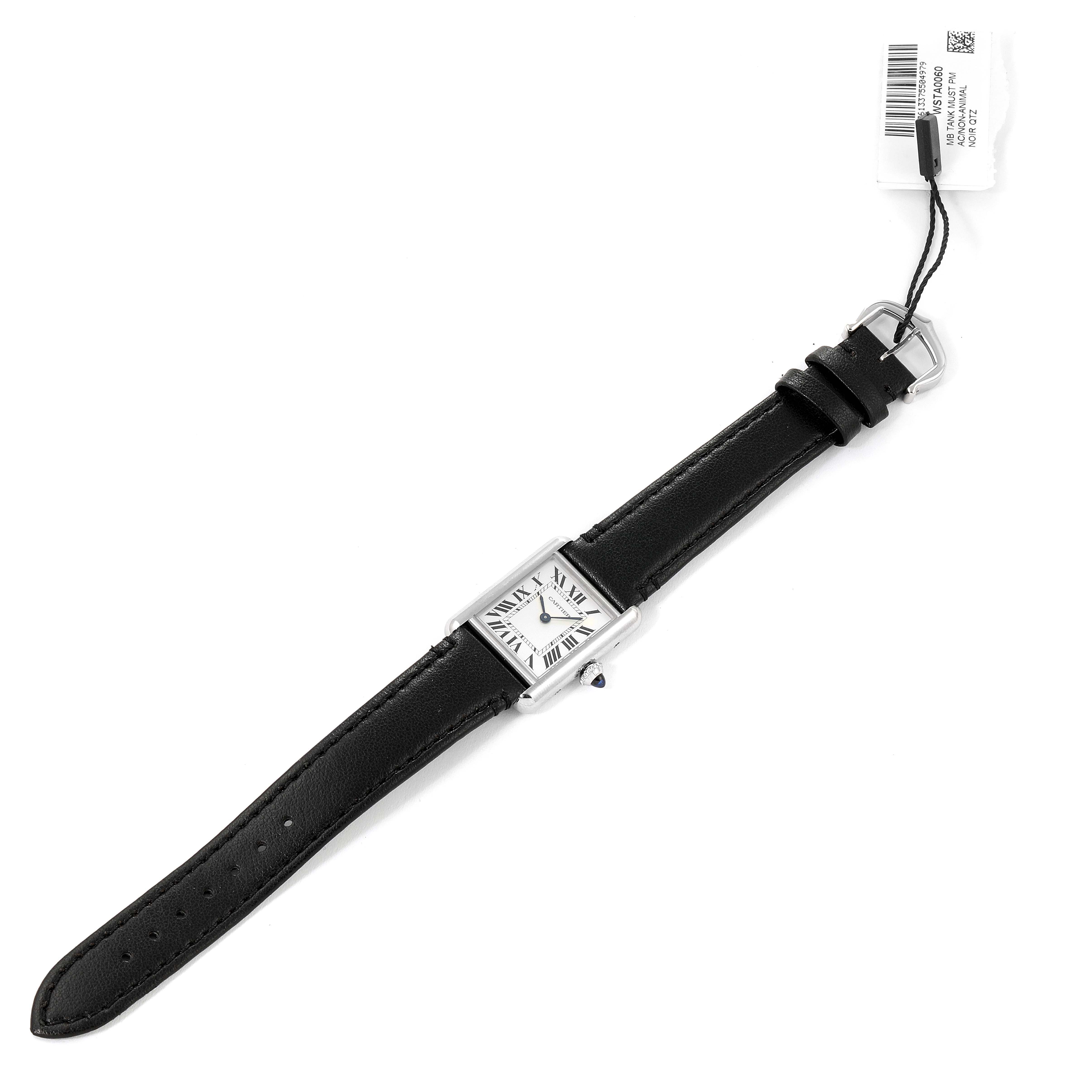 The image shows a top view of the Cartier Tank Must WSTA0060 Women's Stainless Steel Silver Dial WSTA0060 Women's Stainless Steel Silver Dial watch, displaying its face, black leather strap, and tag.