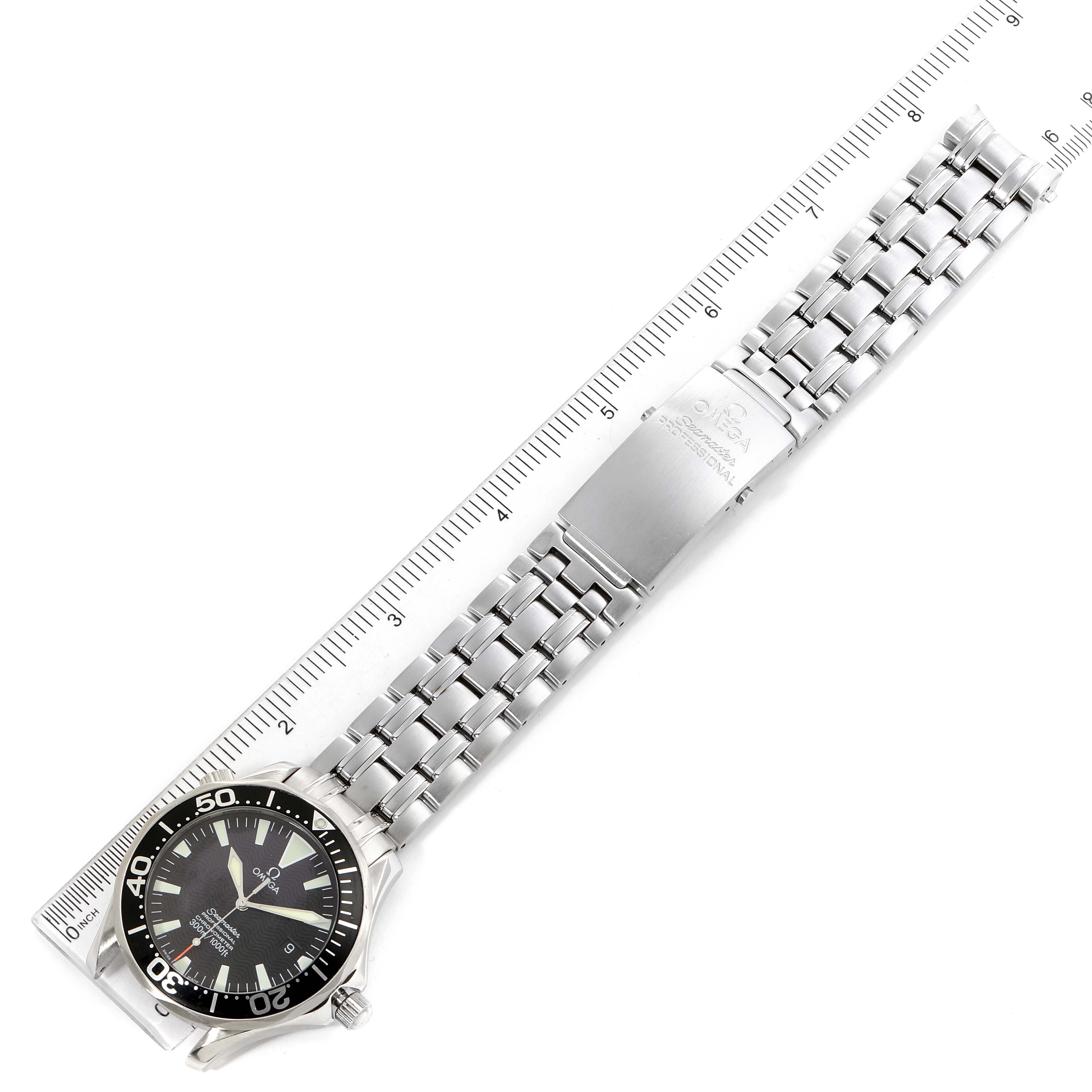 The image shows a top-down view of an Omega Seamaster 2254.50.00 Men
s Stainless Steel Black Dial 2254.50.00 Men
s Stainless Steel Black Dial watch with its stainless steel bracelet and clasp next to a ruler.