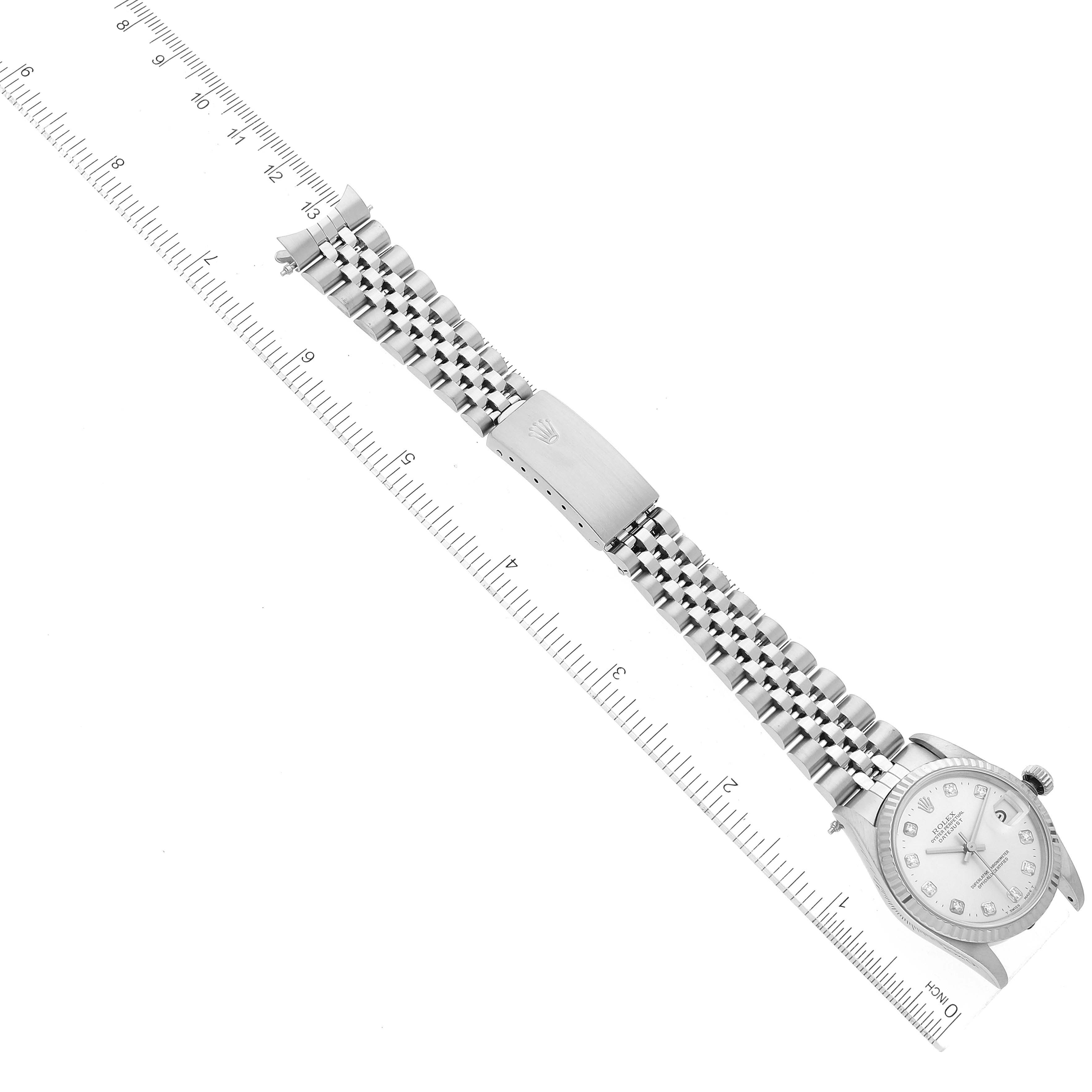The image shows a Mid-Size Rolex watch from a top-down angle, highlighting the watch face, bracelet, and clasp next to a ruler.