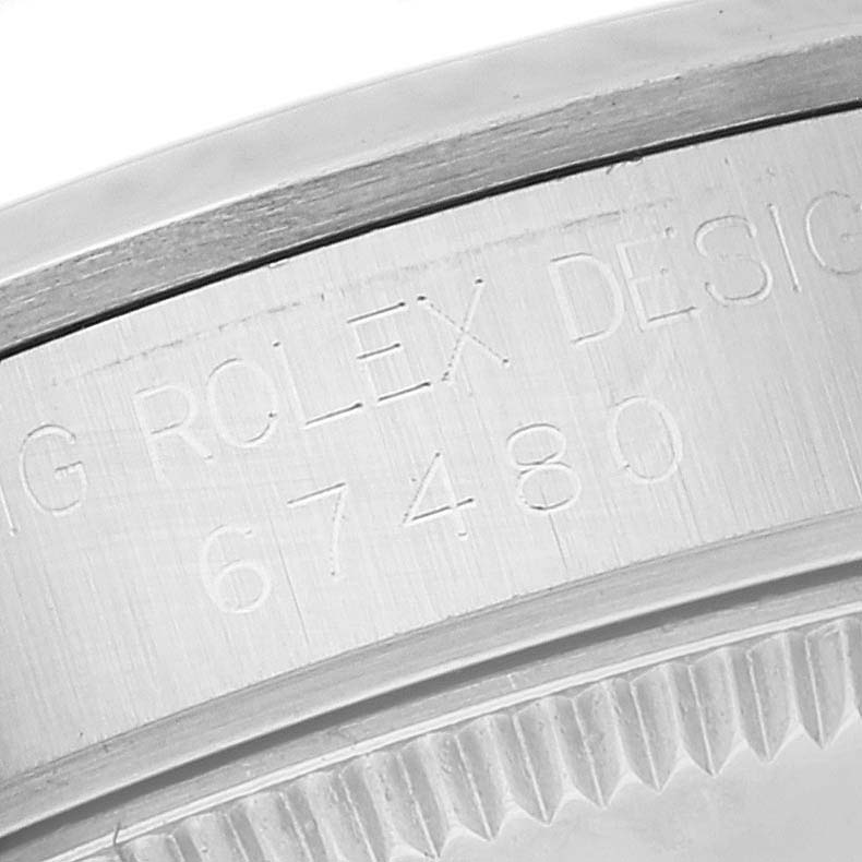 The image shows a close-up of the case back of a Rolex Mid-Size 67480 Women
s Stainless Steel Pink Dial 67480 Women
s Stainless Steel Pink Dial model 67480, highlighting the engraved serial number and design details.