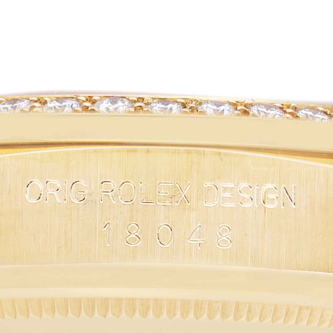 The image shows a close-up of the side of a Rolex President 18048 Men
s Yellow Gold Champagne Dial 18048 Men
s Yellow Gold Champagne Dial model watch, highlighting its design engravings and diamond-set bezel.