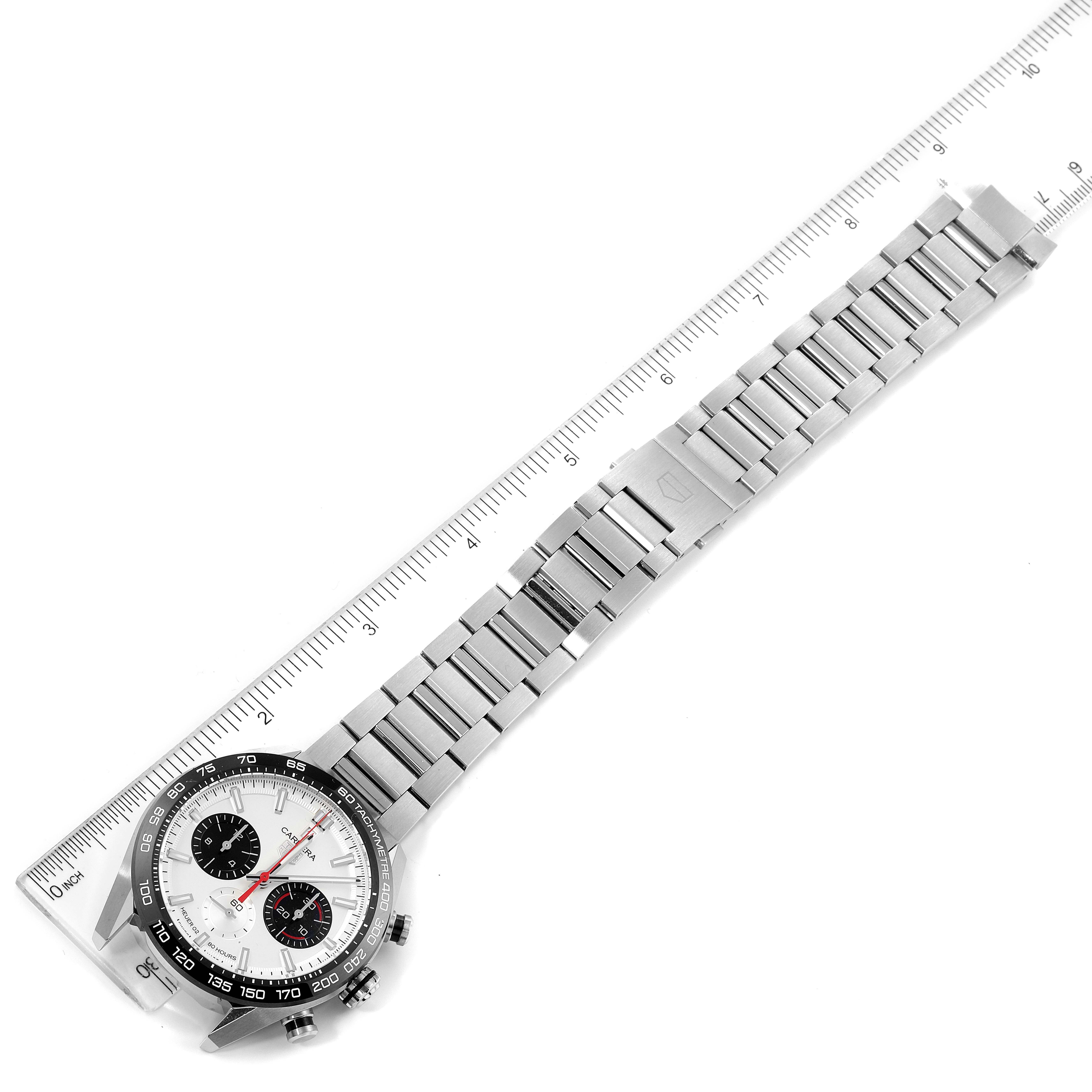 The Tag Heuer Carrera CBN2A1D.BA0643 Men's Stainless Steel Silver Dial CBN2A1D.BA0643 Men's Stainless Steel Silver Dial watch is shown from an overhead angle, displaying its face, metal bracelet, and clasp next to a ruler.