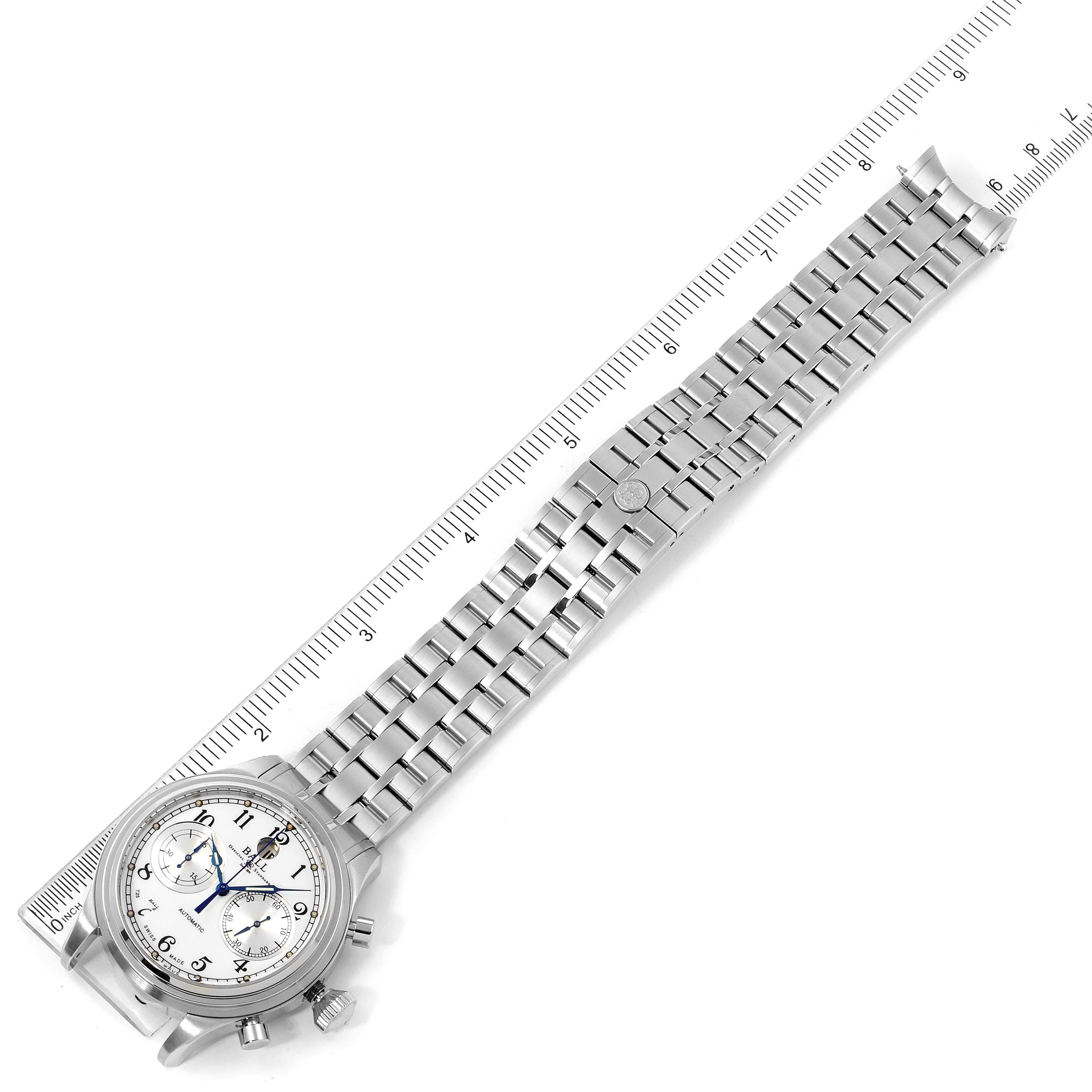 The Ball Trainmaster CM1052D-S3J-WH Men's Stainless Steel White Dial CM1052D-S3J-WH Men's Stainless Steel White Dial watch is shown at an angled top-down view, highlighting its face and metal bracelet alongside a ruler.
