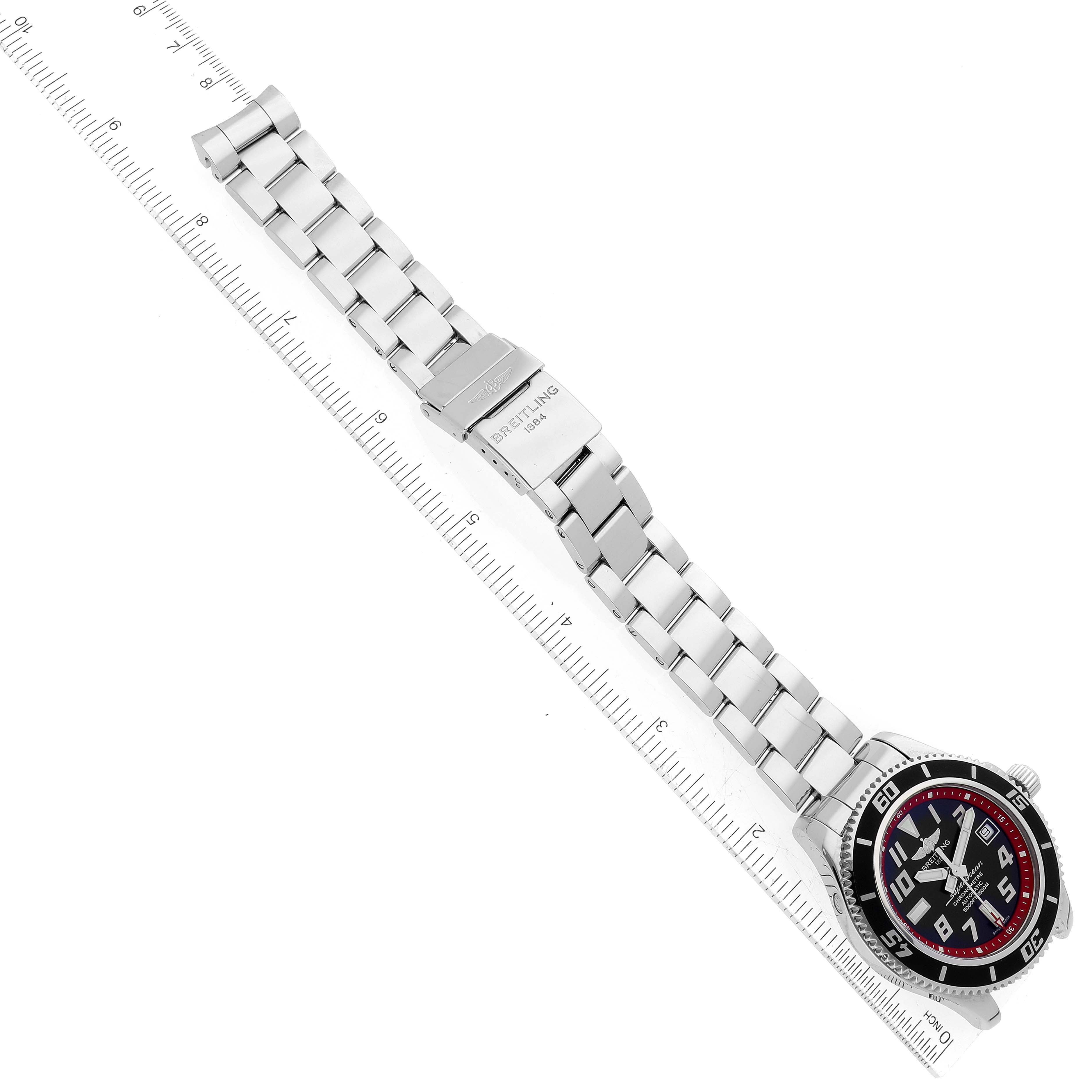 The image shows an overhead view of a Breitling Superocean A1736402/BA31 Men's Stainless Steel Black Dial A1736402/BA31 Men's Stainless Steel Black Dial watch and its metal bracelet, with a ruler beside it for measurement.