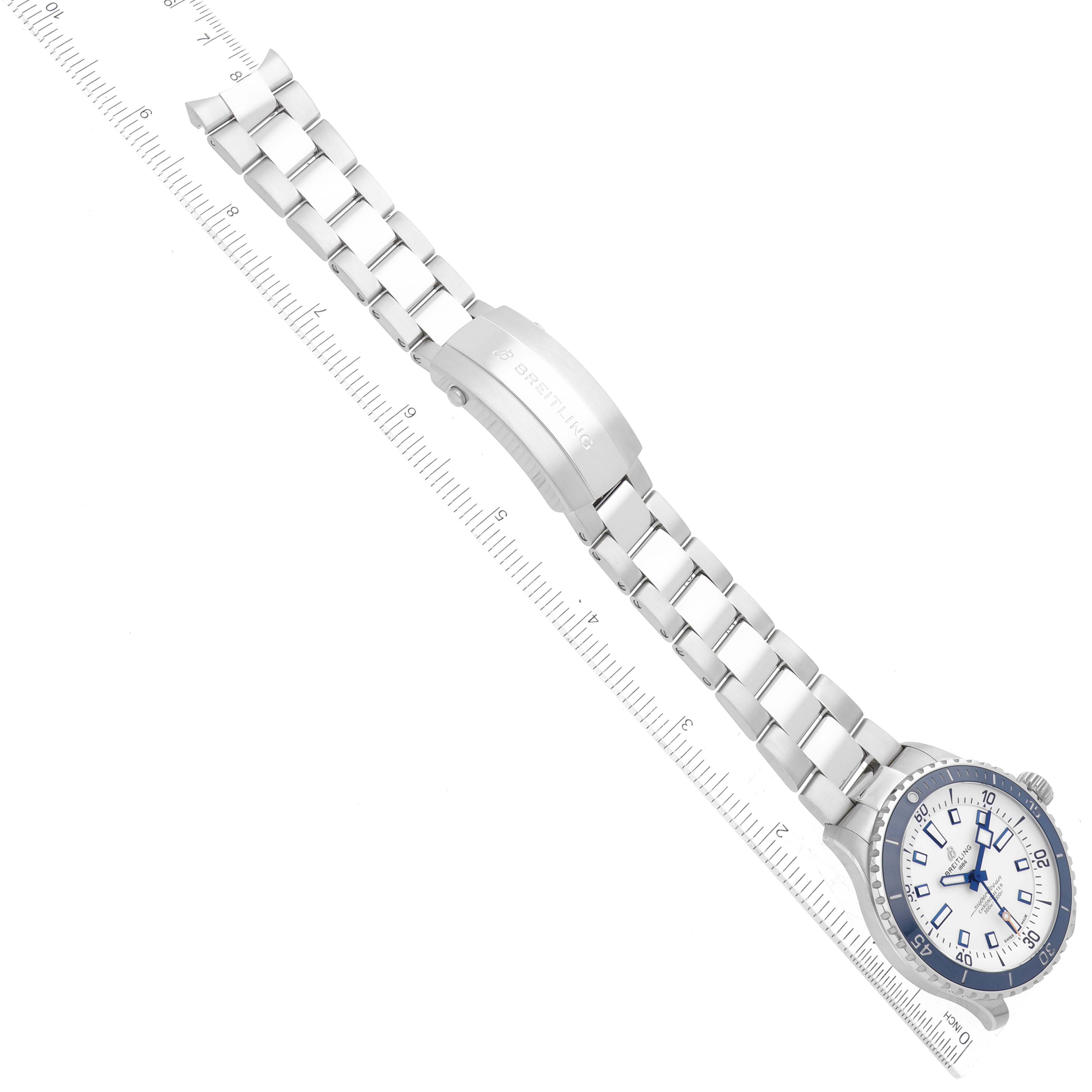 The image shows the face and bracelet of a Breitling Superocean A17375 Men's Stainless Steel White Dial A17375 Men's Stainless Steel White Dial watch from a top view, aligned with a ruler.