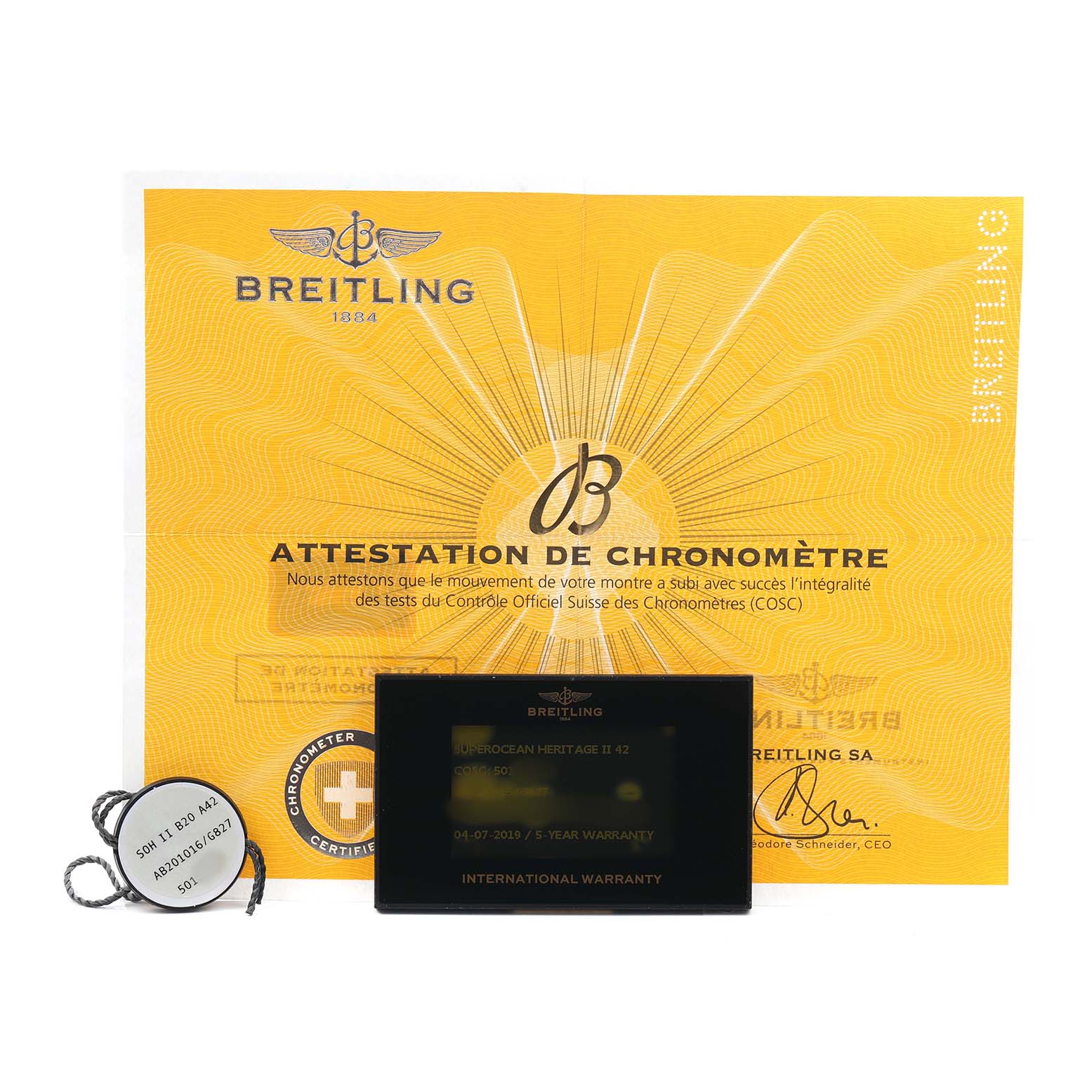 The image shows the Breitling Superocean AB2010 Men's Stainless Steel Silver Dial's warranty card, chronometer certificate, and a tag, all viewed from above.