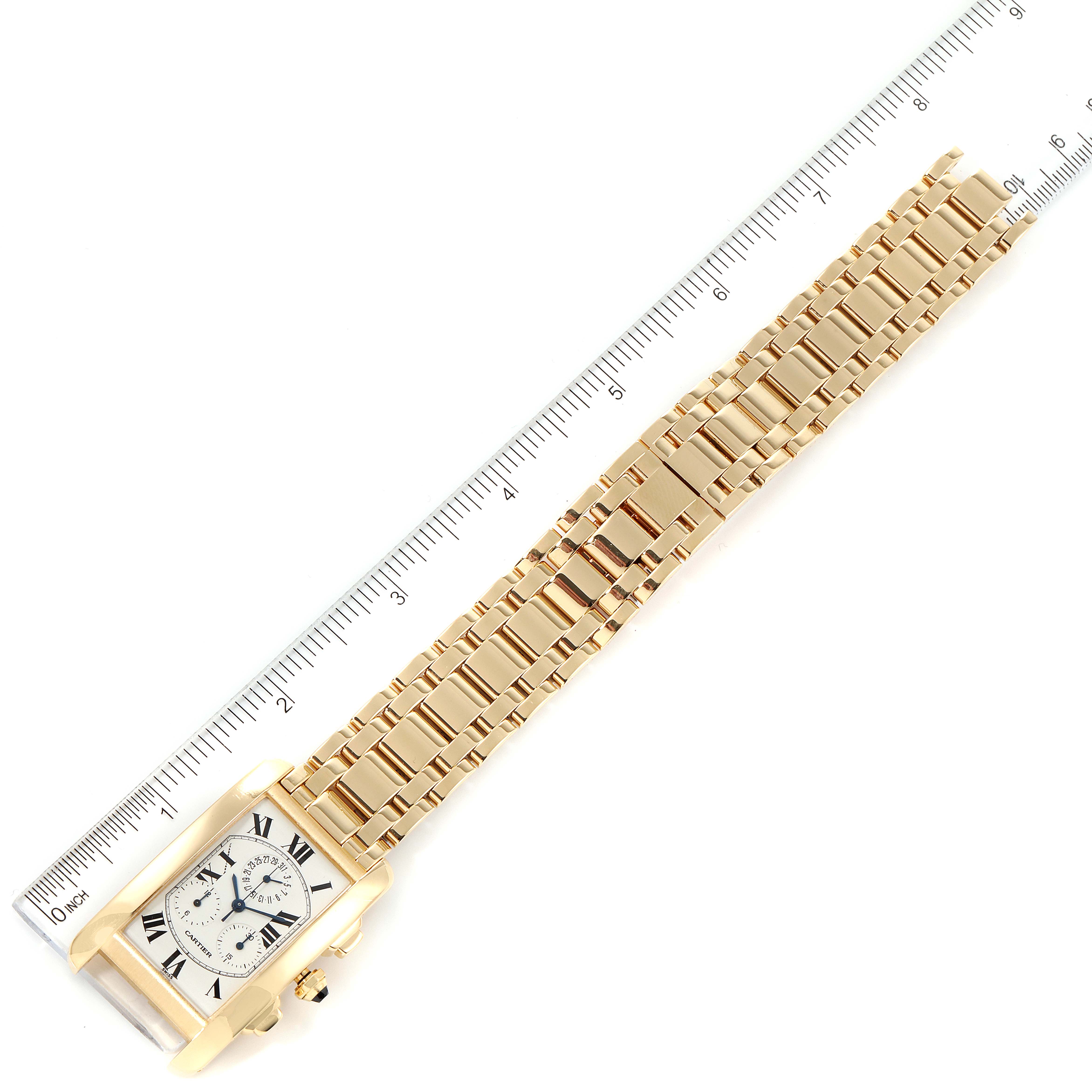 The image shows a Cartier Tank Americaine W2601156 Men
s Yellow Gold Silver Dial W2601156 Men
s Yellow Gold Silver Dial watch laid flat with a gold bracelet band and a ruler for scale.