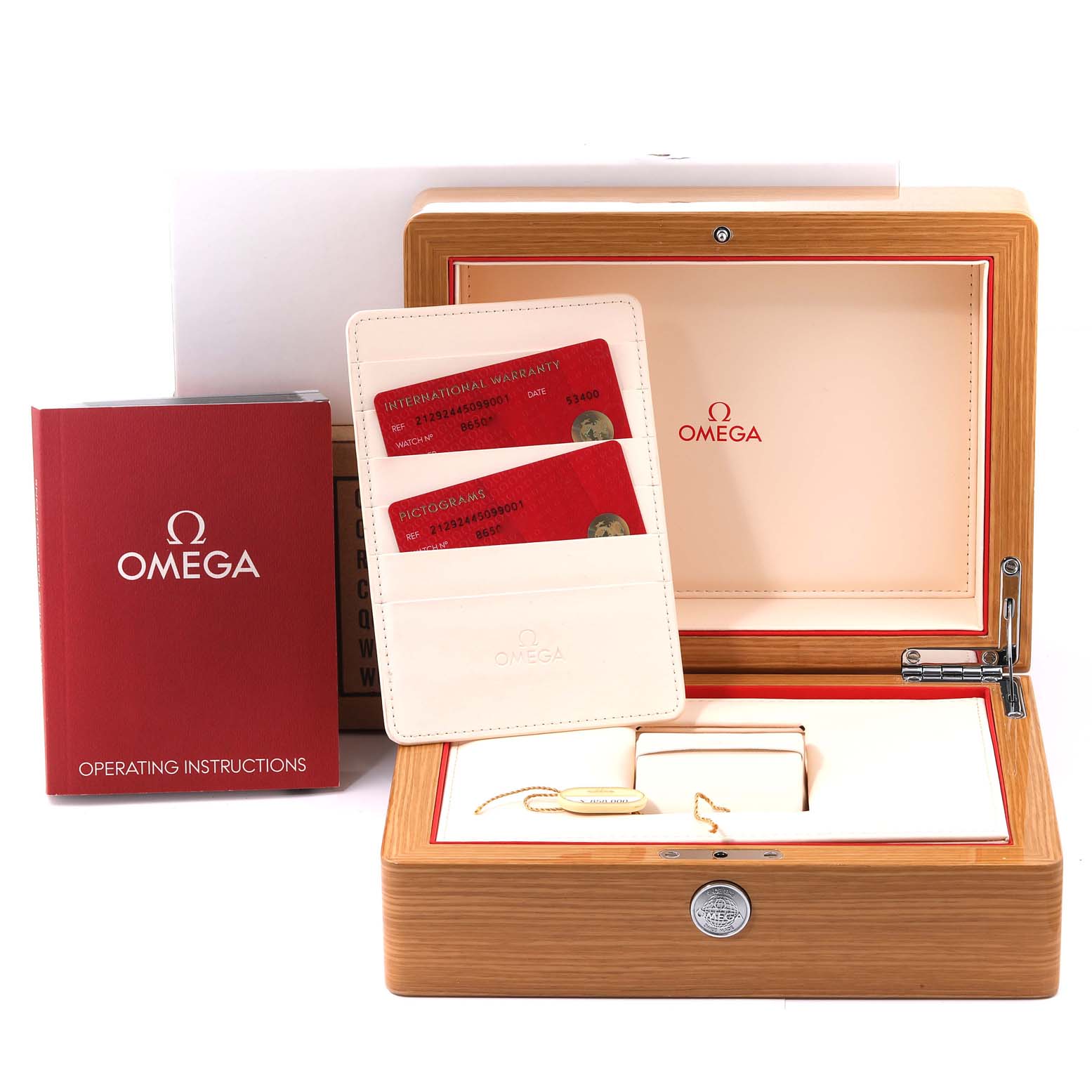 The image shows an open wooden box with Omega branding, warranty cards, a red operating instructions booklet, and a tag for the Seamaster model by Omega.