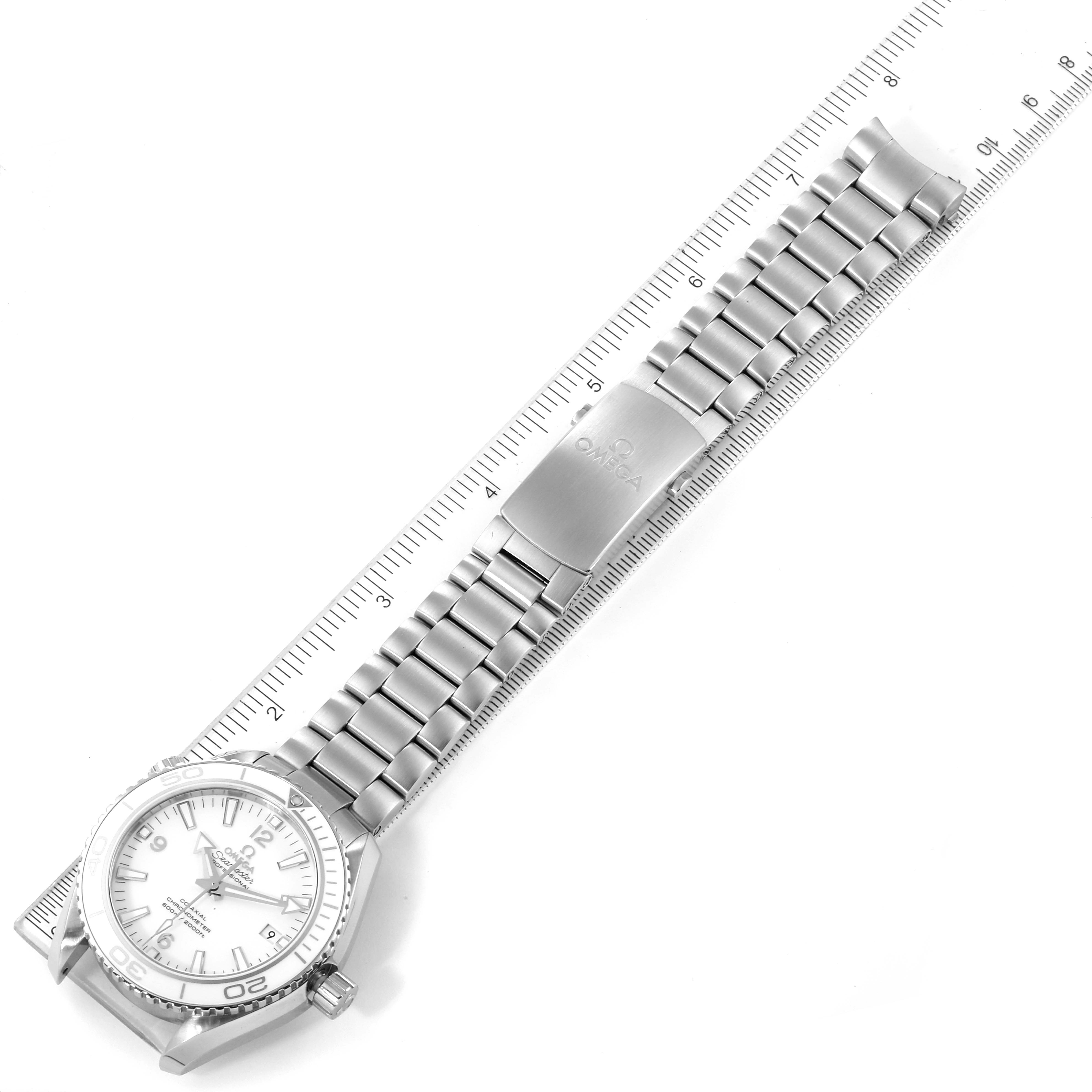 The image shows an Omega Planet Ocean 232.30.42.21.04.001 Men's Stainless Steel White Dial 232.30.42.21.04.001 Men's Stainless Steel White Dial watch laid flat, displaying the dial, case, crown, and full bracelet against a ruler.