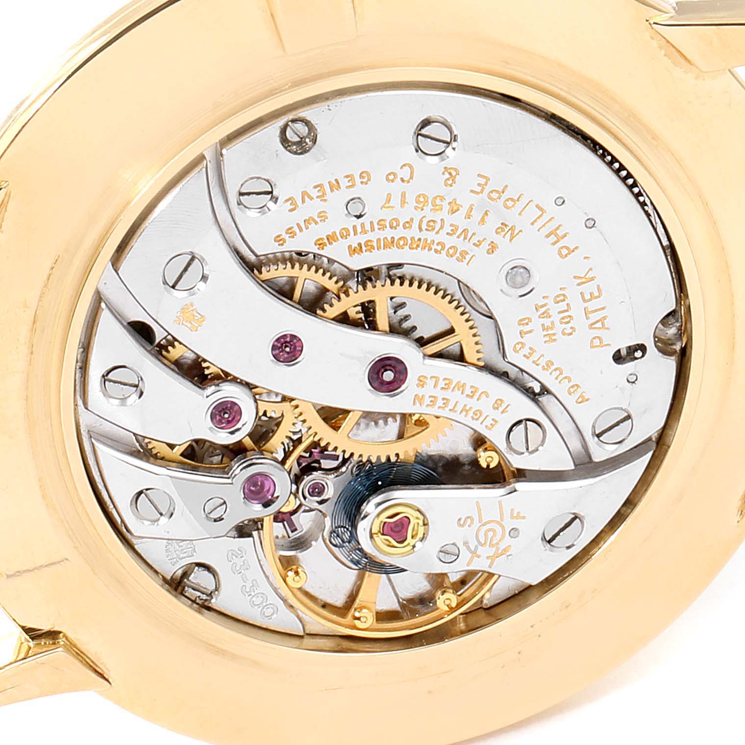 This is a close-up shot of the movement mechanism on the back of a Vintage Patek Philippe watch, displaying gears and engravings.