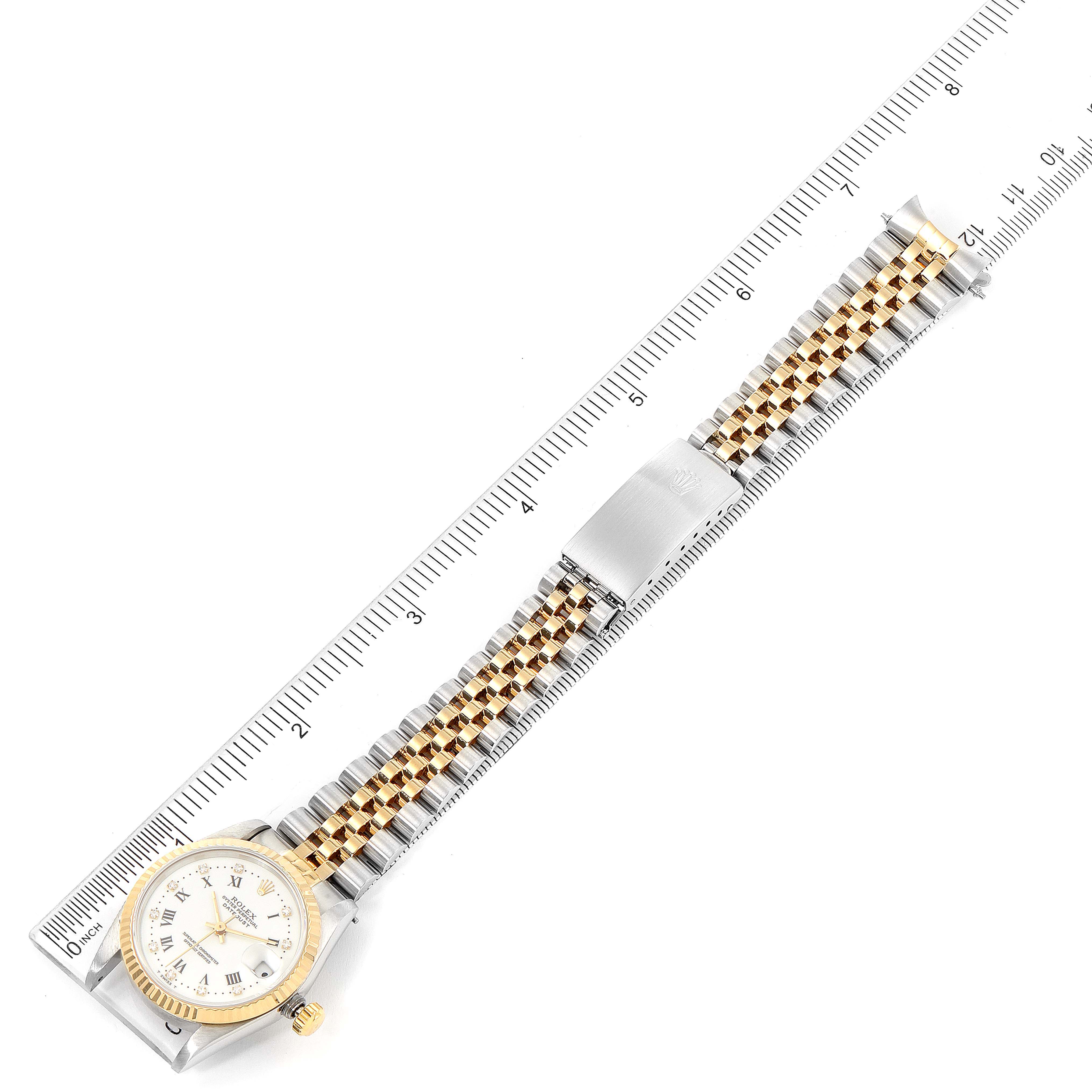 The image shows a top-down view of a Rolex Mid-Size 68273 Women
s Steel and Gold (two tone) White Dial 68273 Women
s Steel and Gold (two tone) White Dial watch, displaying its face, bezel, and band alongside a ruler for scale.
