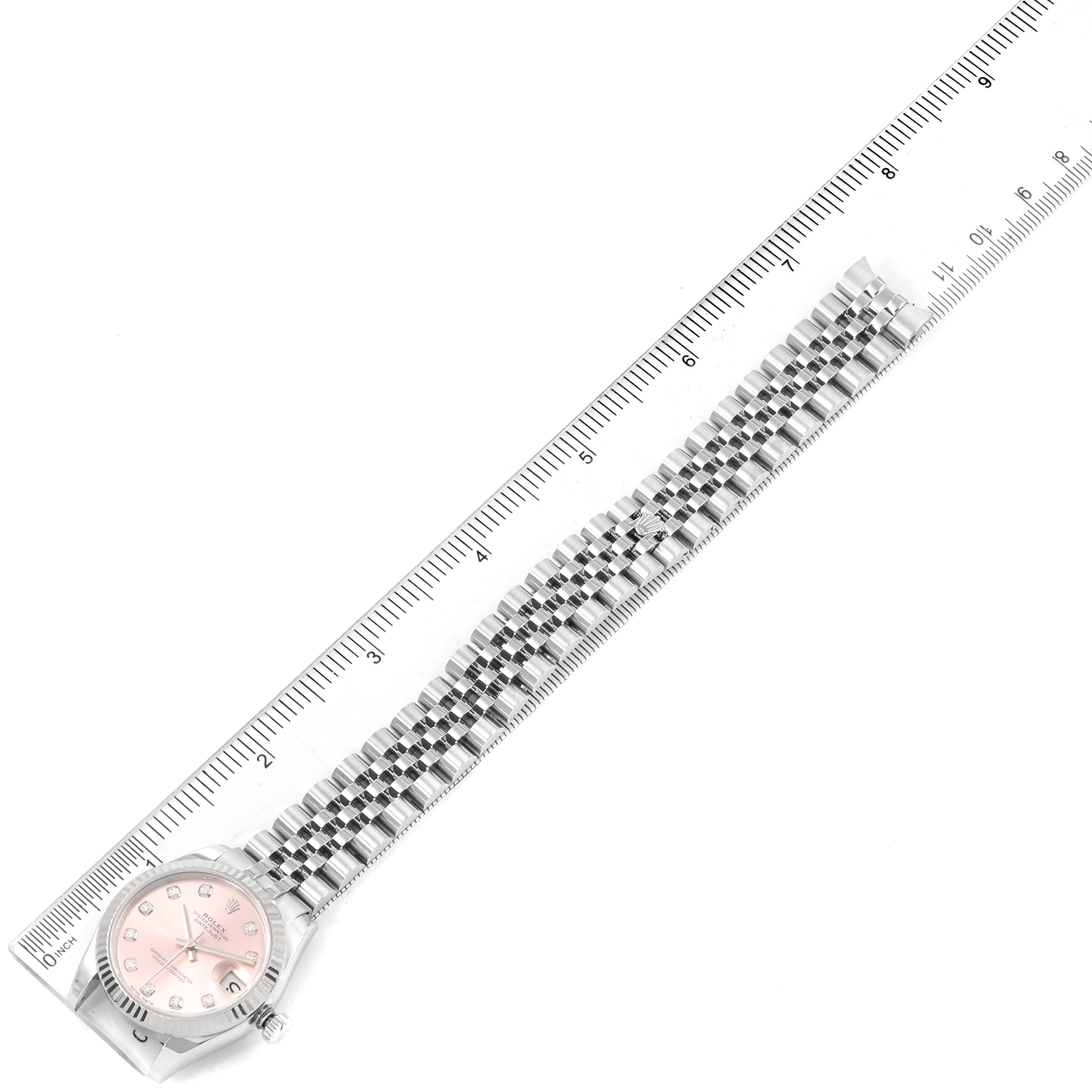 The image shows a top-down view of a Rolex Mid-Size 178274 Women's Stainless Steel Pink Dial 178274 Women's Stainless Steel Pink Dial watch with a pink dial and a metal bracelet, measured against a ruler.