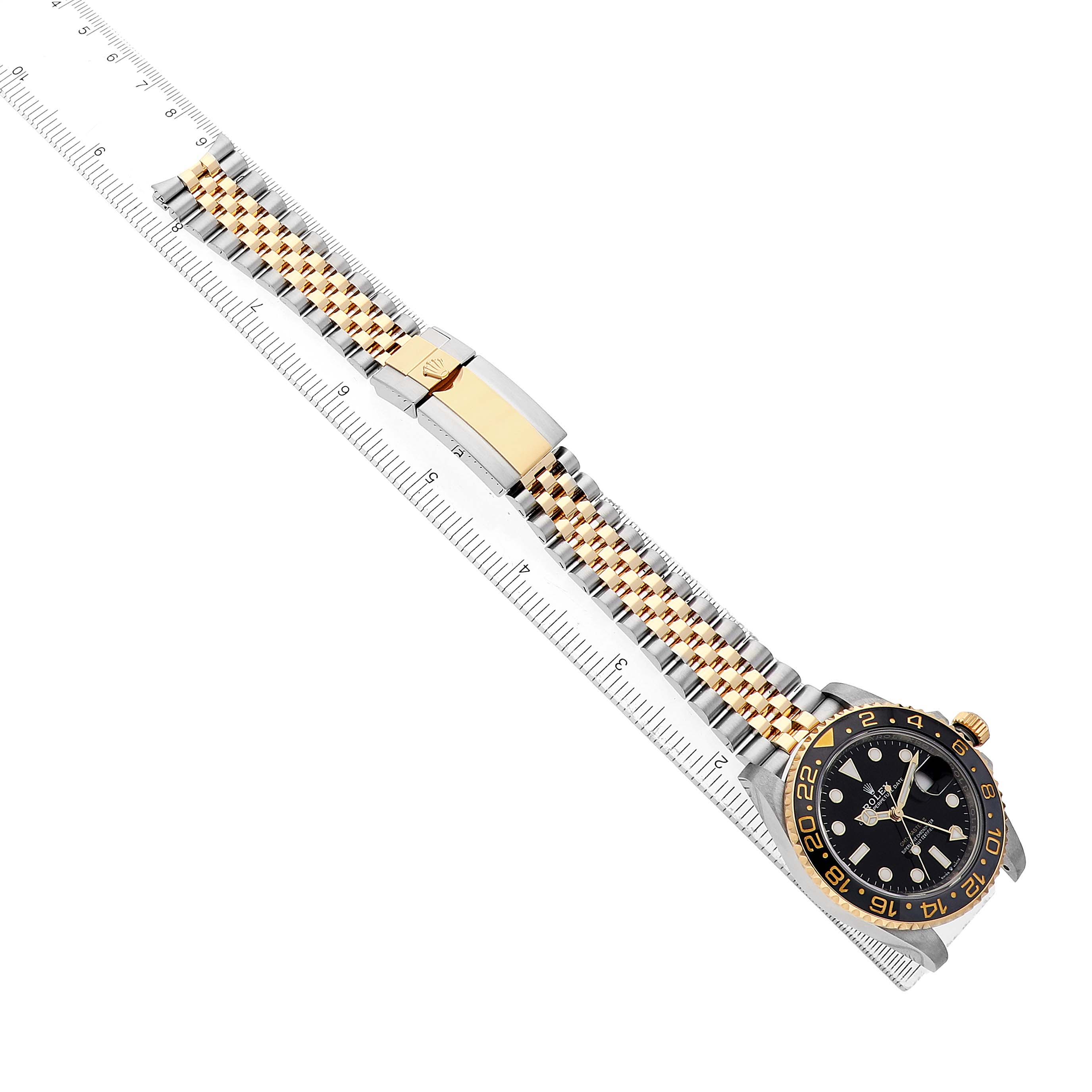 The Rolex GMT-Master 126713 Men's Steel and Gold (two tone) Black Dial watch is shown from an angled top view, displaying the face and a two-tone bracelet alongside a measuring ruler.