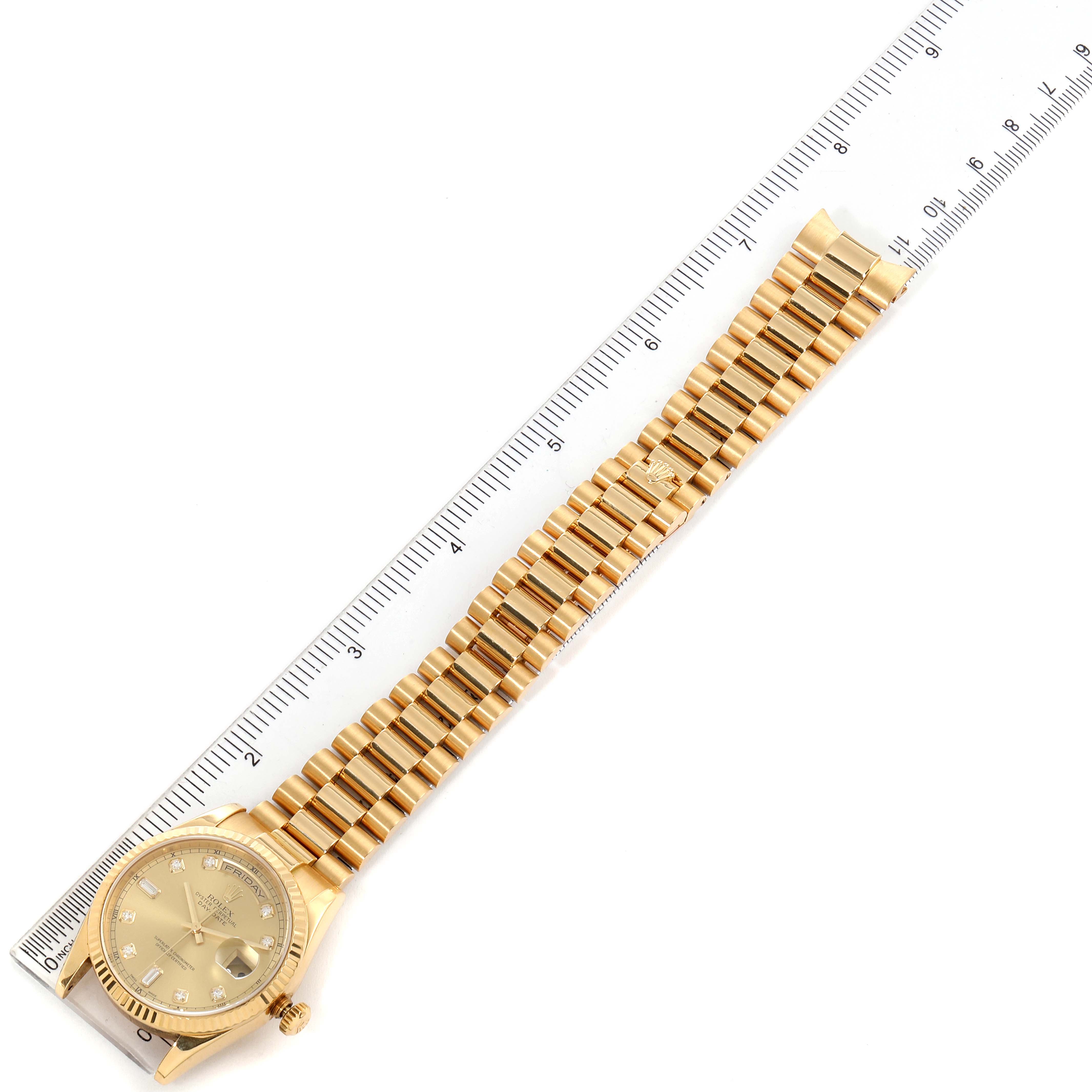 The image shows a top-down view of a Rolex President 118238 Men
s Yellow Gold Champagne Dial 118238 Men
s Yellow Gold Champagne Dial model watch, displaying the face and the full gold bracelet against a ruler.