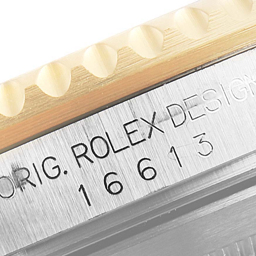 This close-up image shows the side engraving and part of the bezel of a Rolex Submariner 16613 Men's Steel and Gold (two tone) Black Dial 16613 Men's Steel and Gold (two tone) Black Dial 16613 watch.