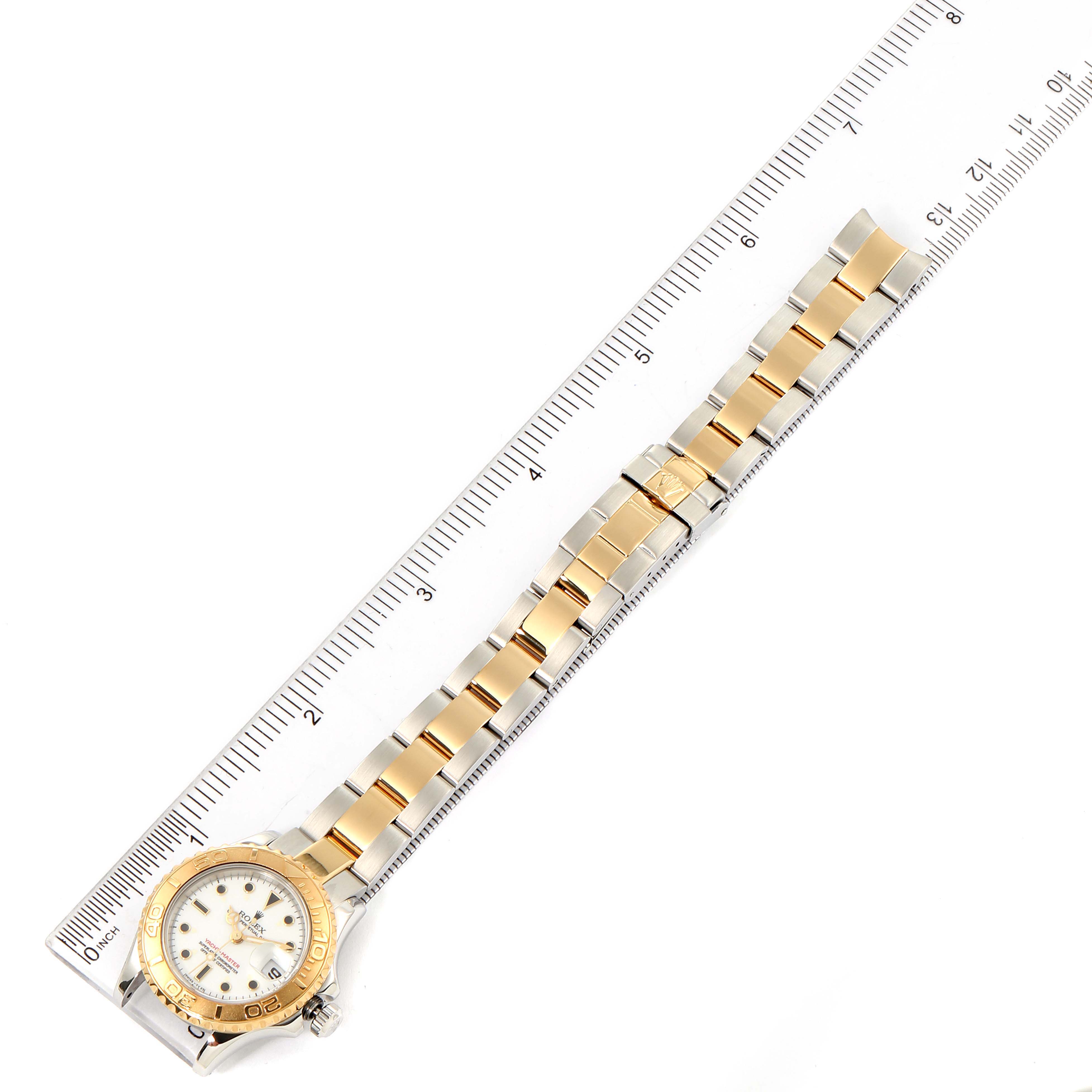 The Rolex Yacht-Master 69623 Women's Steel and Gold (two tone) White Dial 69623 Women's Steel and Gold (two tone) White Dial watch is shown from an overhead angle along with its full bracelet against a ruler for scale.