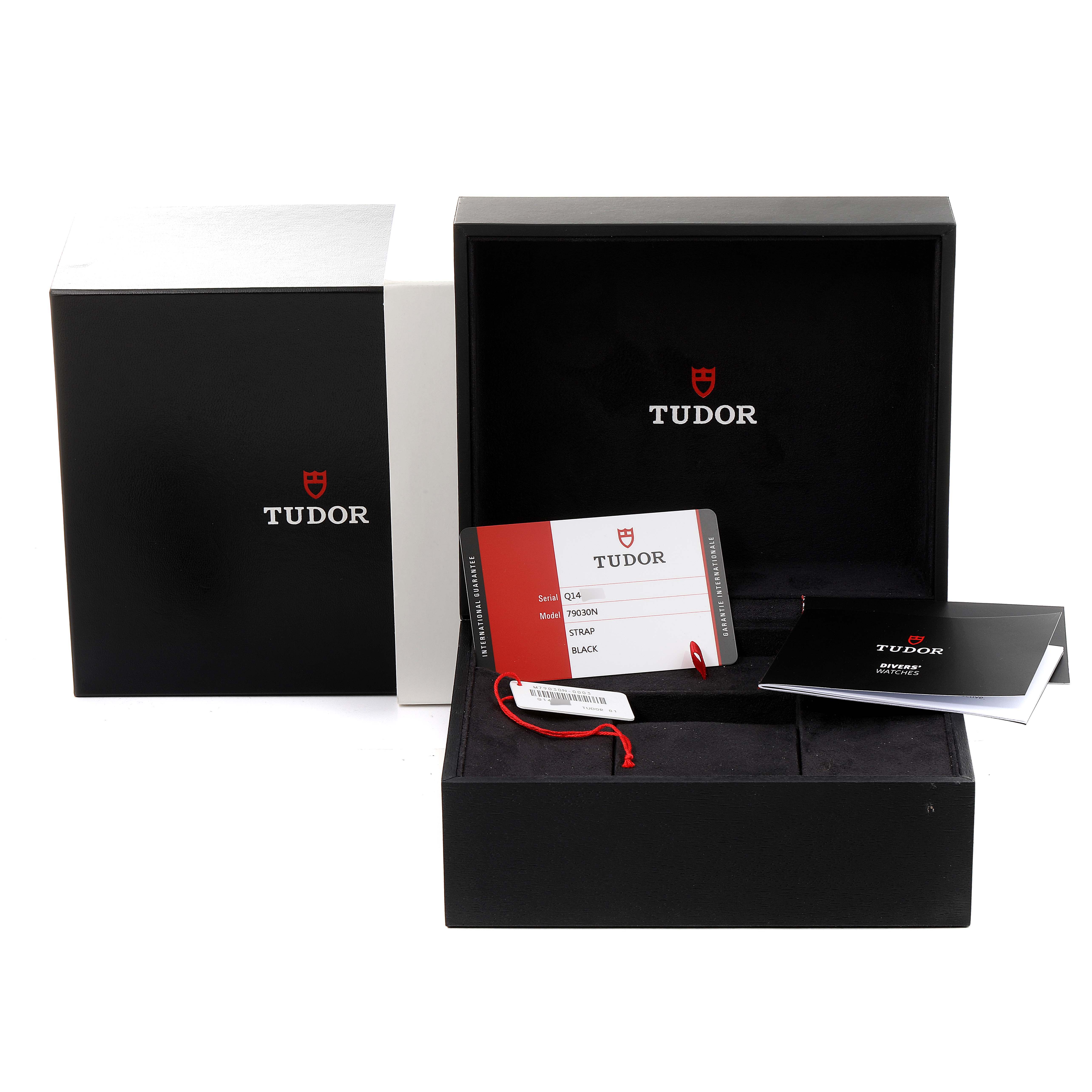 The image shows the packaging and accessories for a Tudor Heritage Black Bay 79030N Men
s Stainless Steel Black Dial 79030N Men
s Stainless Steel Black Dial watch, including its box, warranty card, and manual.