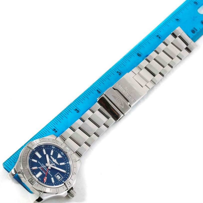 The image shows a Breitling Avenger A32390 Men's Stainless Steel Blue Dial A32390 Men's Stainless Steel Blue Dial watch laid flat with a blue ruler beside it, displaying the watch's metal bracelet and clasp.