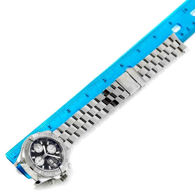 The image shows a flat angle view of a Breitling Superocean A13340 Men's Stainless Steel Grey Dial A13340 Men's Stainless Steel Grey Dial watch, highlighting its face, bezel, and metal bracelet alongside a blue ruler.