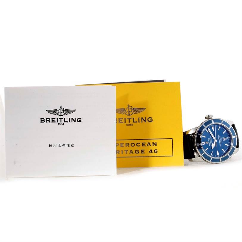 The image shows a Breitling Superocean A17320 Men's Stainless Steel Blue Dial A17320 Men's Stainless Steel Blue Dial watch partially with its blue face, alongside its manuals and warranty card.