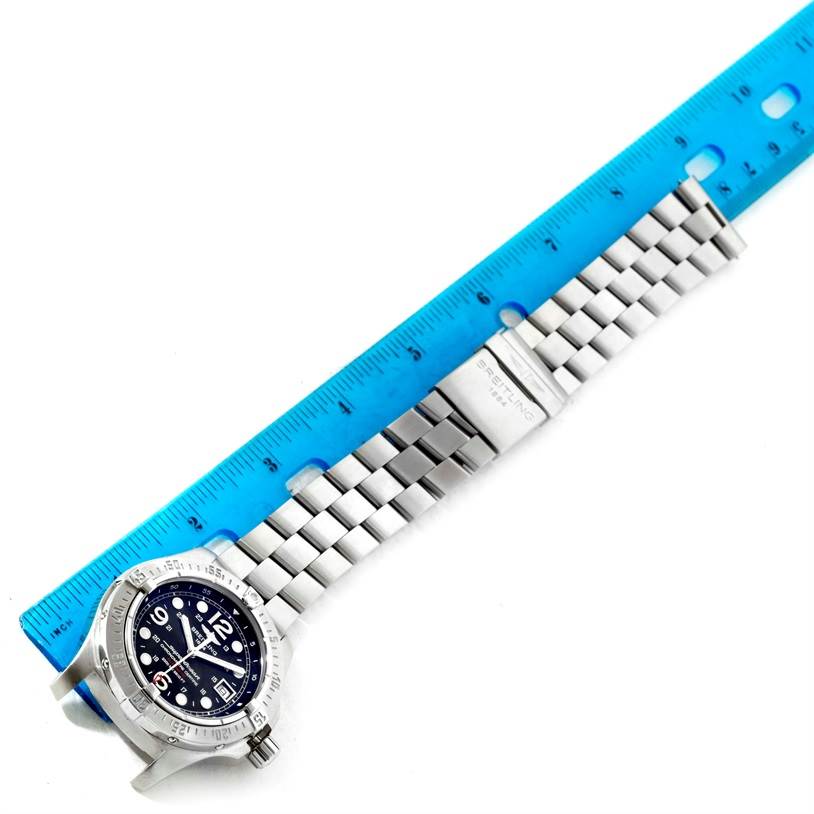 The image shows a Breitling Superocean A17390 Men's Stainless Steel Black Dial A17390 Men's Stainless Steel Black Dial watch laid flat with its face and metal bracelet band fully visible, alongside a blue ruler for scale.