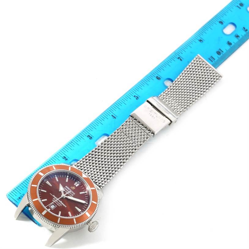 The Breitling Superocean A17320 Men
s Stainless Steel Brown Dial A17320 Men
s Stainless Steel Brown Dial watch is shown from a top-down angle, highlighting its orange bezel, dial, and mesh bracelet.