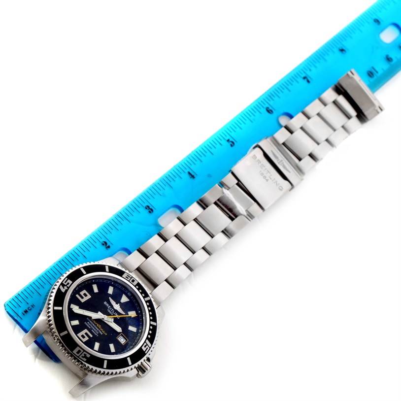 The image shows a Breitling Superocean A17391 Men's Stainless Steel Black Dial A17391 Men's Stainless Steel Black Dial watch placed horizontally alongside a blue ruler, displaying both the watch face and stainless steel bracelet.