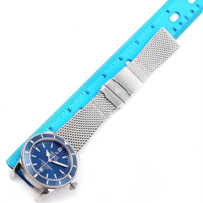 The Breitling Superocean A17320 Men's Stainless Steel Blue Dial A17320 Men's Stainless Steel Blue Dial watch is displayed face-up alongside a ruler, showing its stainless steel mesh strap and blue dial.