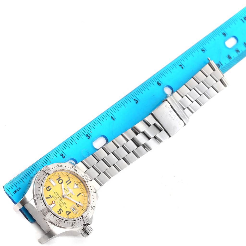 The Breitling Avenger A17330 Men's Stainless Steel Yellow Dial A17330 Men's Stainless Steel Yellow Dial watch is shown from an overhead angle, displaying the face, case, bezel, and metal bracelet next to a ruler.