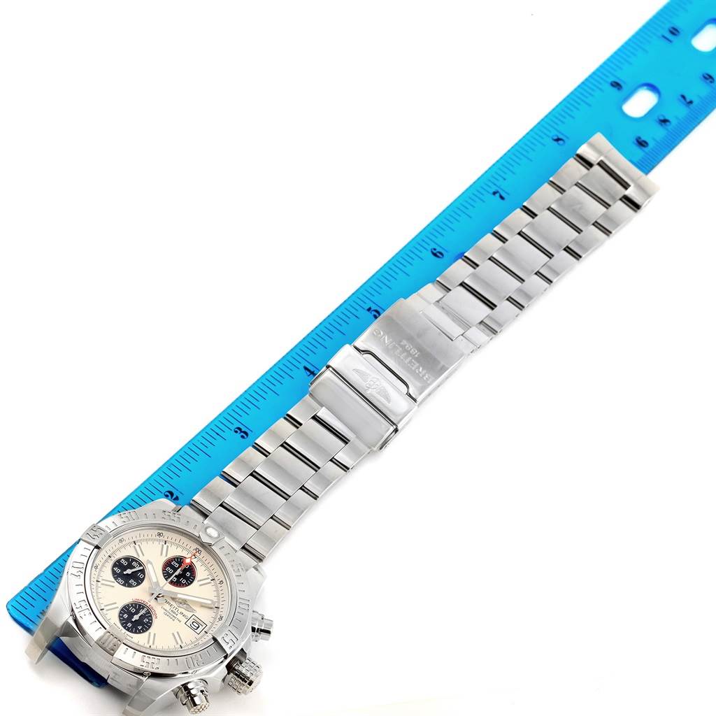 The Breitling Avenger A13381 Men's Stainless Steel White Dial A13381 Men's Stainless Steel White Dial watch is shown from a top-down angle, displaying the face, bezel, and metal bracelet alongside a blue ruler.