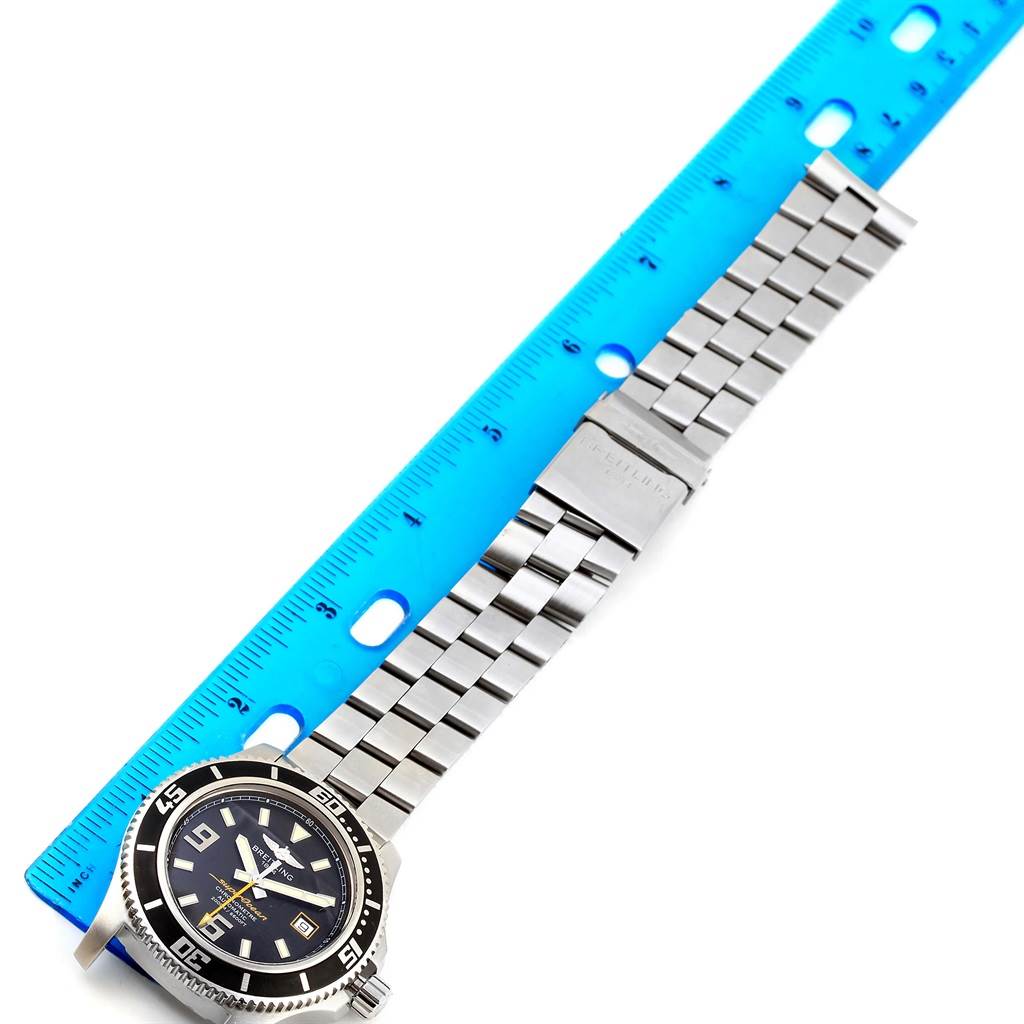 The image shows a Breitling Superocean A17391 Men's Stainless Steel Black Dial A17391 Men's Stainless Steel Black Dial watch laying flat against a blue ruler, displaying its dial, bezel, and metal bracelet.