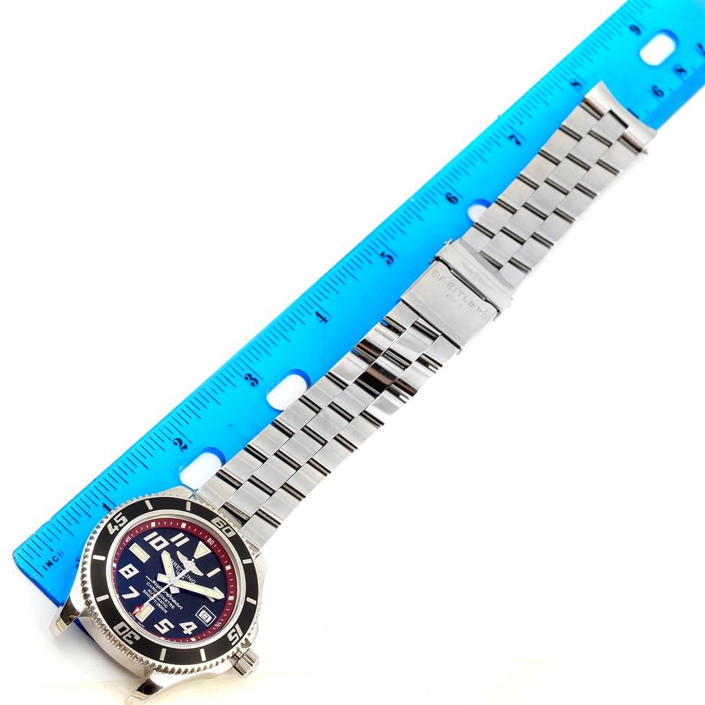 The image shows a Breitling Superocean A17364 Men's Stainless Steel Black Dial A17364 Men's Stainless Steel Black Dial watch laid flat next to a blue ruler, displaying its dial and metal bracelet.