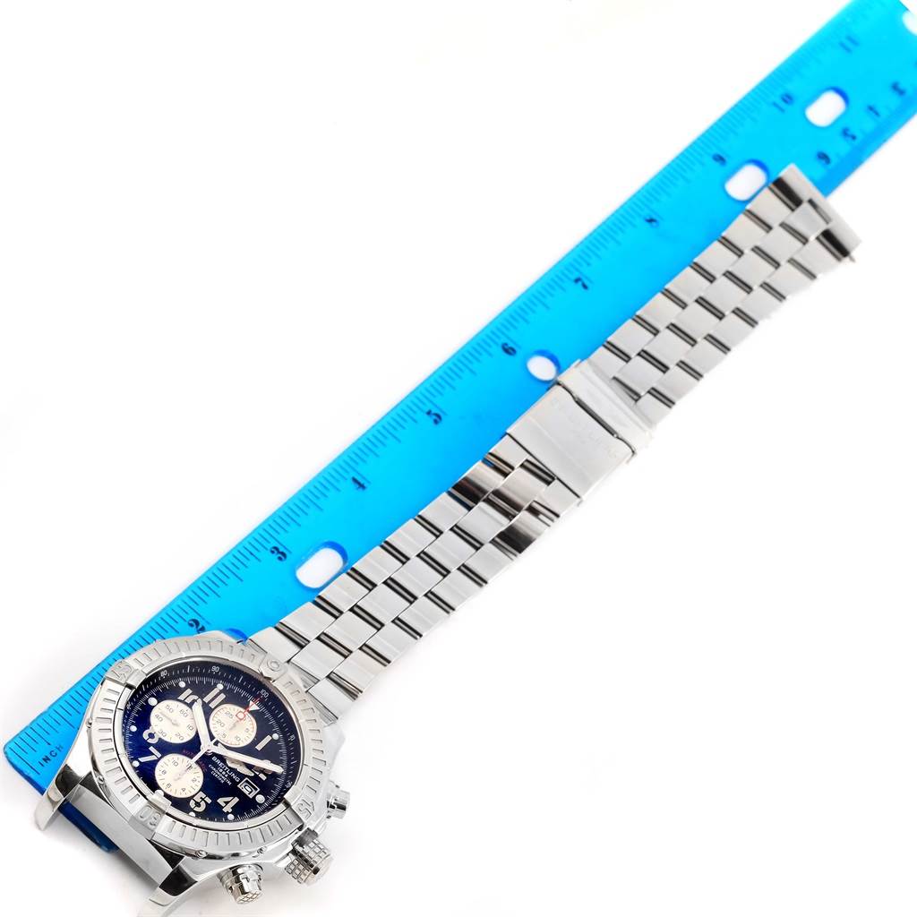 The Breitling Avenger A13370 Men's Stainless Steel Black Dial A13370 Men's Stainless Steel Black Dial watch is shown from an overhead angle alongside a blue ruler, displaying the face, bezel, and full metal bracelet.