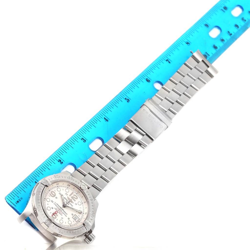 The Breitling Superocean A17390 Men's Stainless Steel Silver Dial A17390 Men's Stainless Steel Silver Dial watch is shown from a top-down angle, fully displaying the bracelet and face alongside a blue ruler.