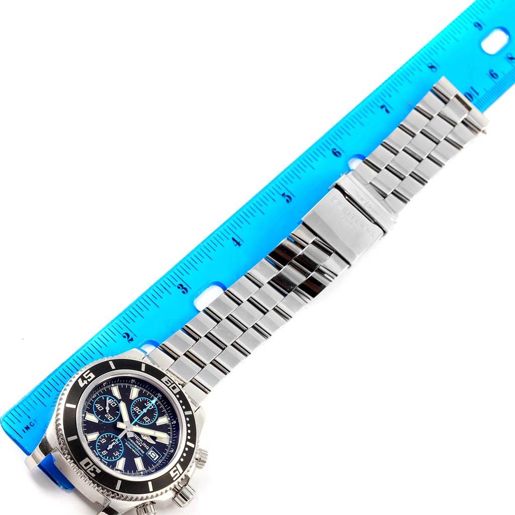 The Breitling Superocean A13341 Men's Stainless Steel Black Dial A13341 Men's Stainless Steel Black Dial watch is shown at an angle with its face and metal bracelet lying flat next to a blue ruler.