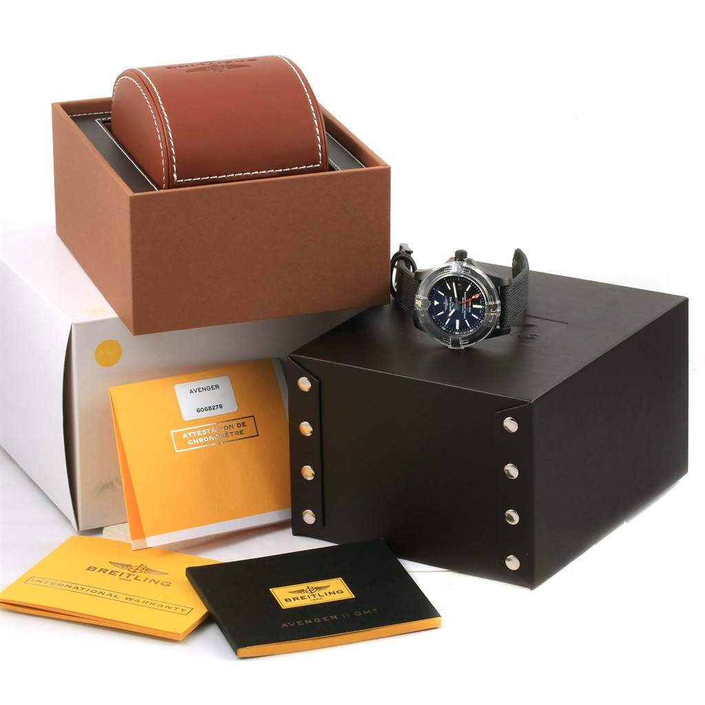 The image shows a Breitling Avenger M32390 Men's Stainless Steel Black Dial M32390 Men's Stainless Steel Black Dial watch alongside its box, leather case, and accompanying booklets from an angled top view.