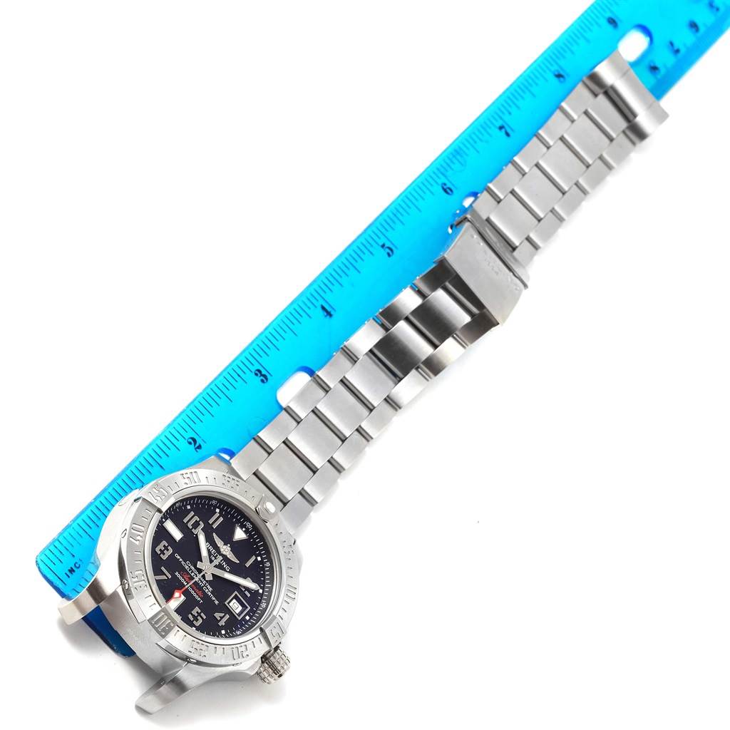 The image shows a top-down view of a Breitling Avenger A17331 Men's Stainless Steel Black Dial A17331 Men's Stainless Steel Black Dial watch with a metal bracelet resting alongside a ruler for scale.