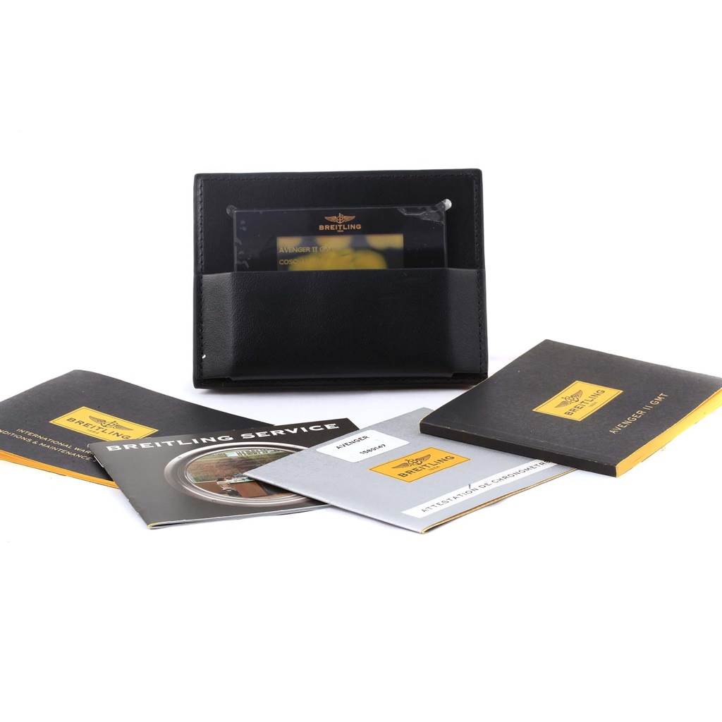 The image shows the accessories for a Breitling Avenger A32390 Men's Stainless Steel Black Dial A32390 Men's Stainless Steel Black Dial, including manuals, a service book, and a black leather cardholder.