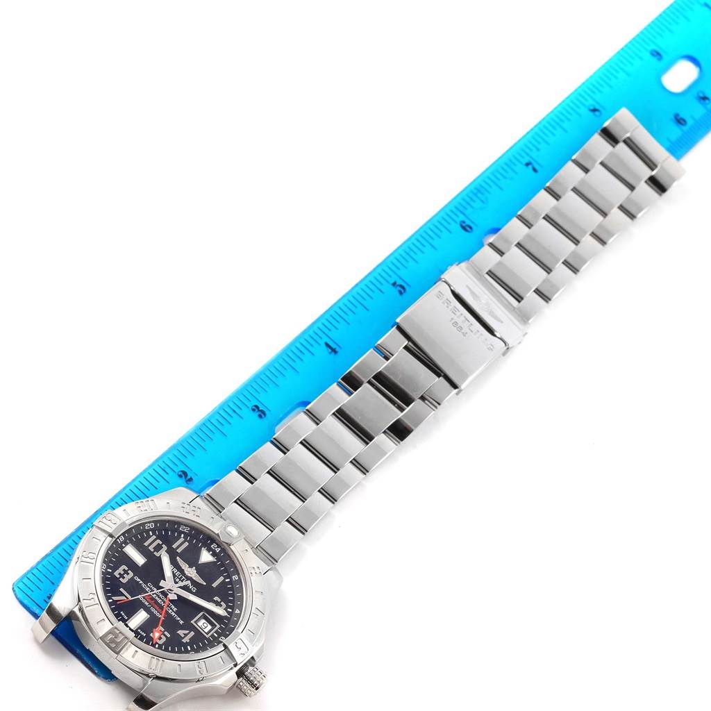 The image shows a top-down view of a Breitling Avenger A32390 Men's Stainless Steel Black Dial A32390 Men's Stainless Steel Black Dial watch with its metal bracelet fully extended next to a blue ruler.