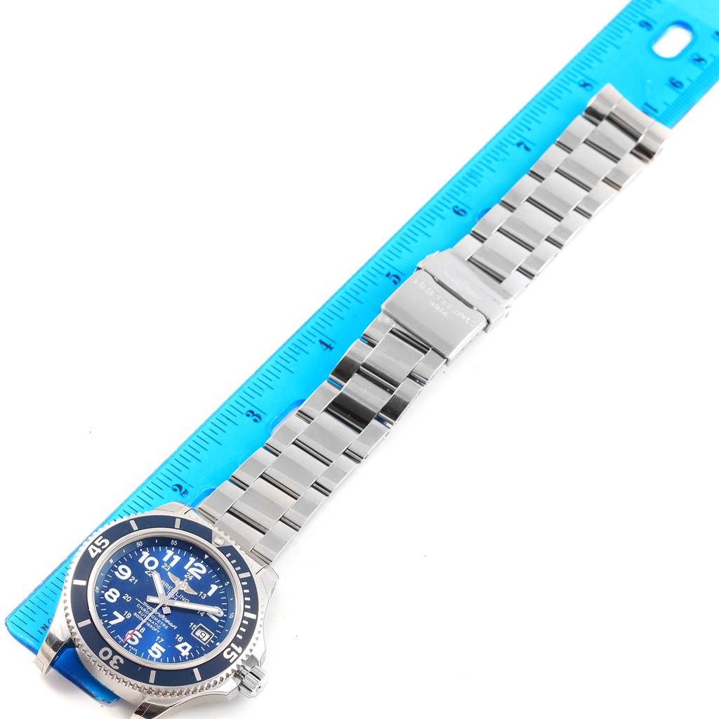 The image shows a top-down view of a Breitling Superocean A17365 Men's Stainless Steel Blue Dial A17365 Men's Stainless Steel Blue Dial watch with a blue dial, stainless steel case, and bracelet next to a ruler.